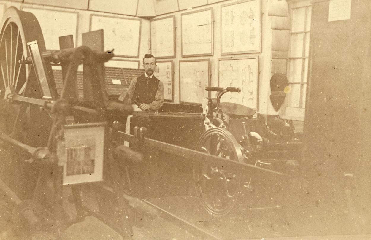 Sepia photograph of a man demonstrating machinery in public