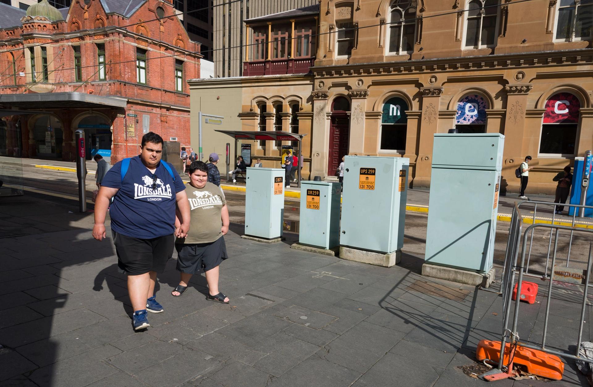 Father and son walk towards the camera, they are both wearing Londsdale London tshirts, one navy and one beige.