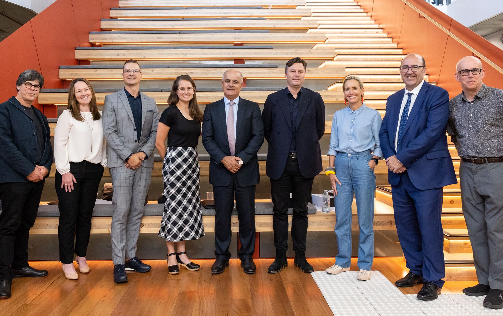 Line up of people smiling at the camera, in front of amphitheatre seating.