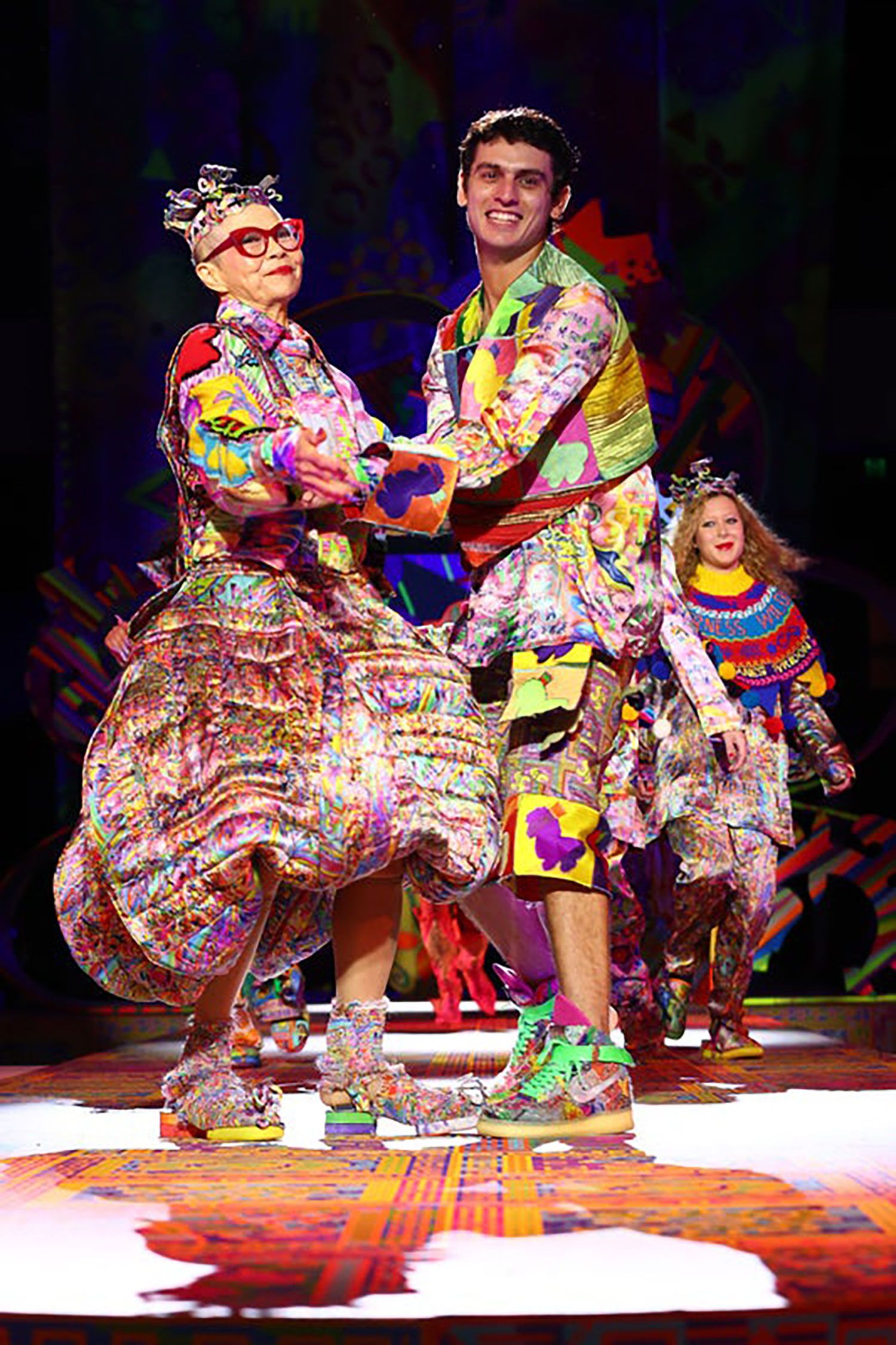 Jordan Gogos and Jenny Kee pose on the runway and hold each others arms.