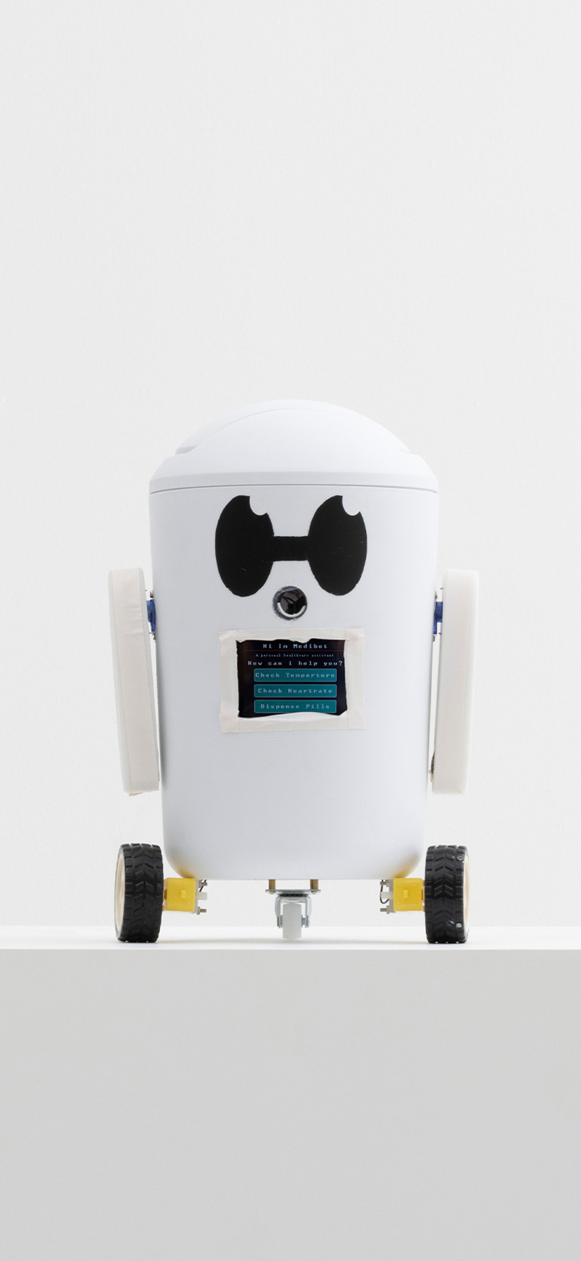little white robot on wheels sitting on a plinth