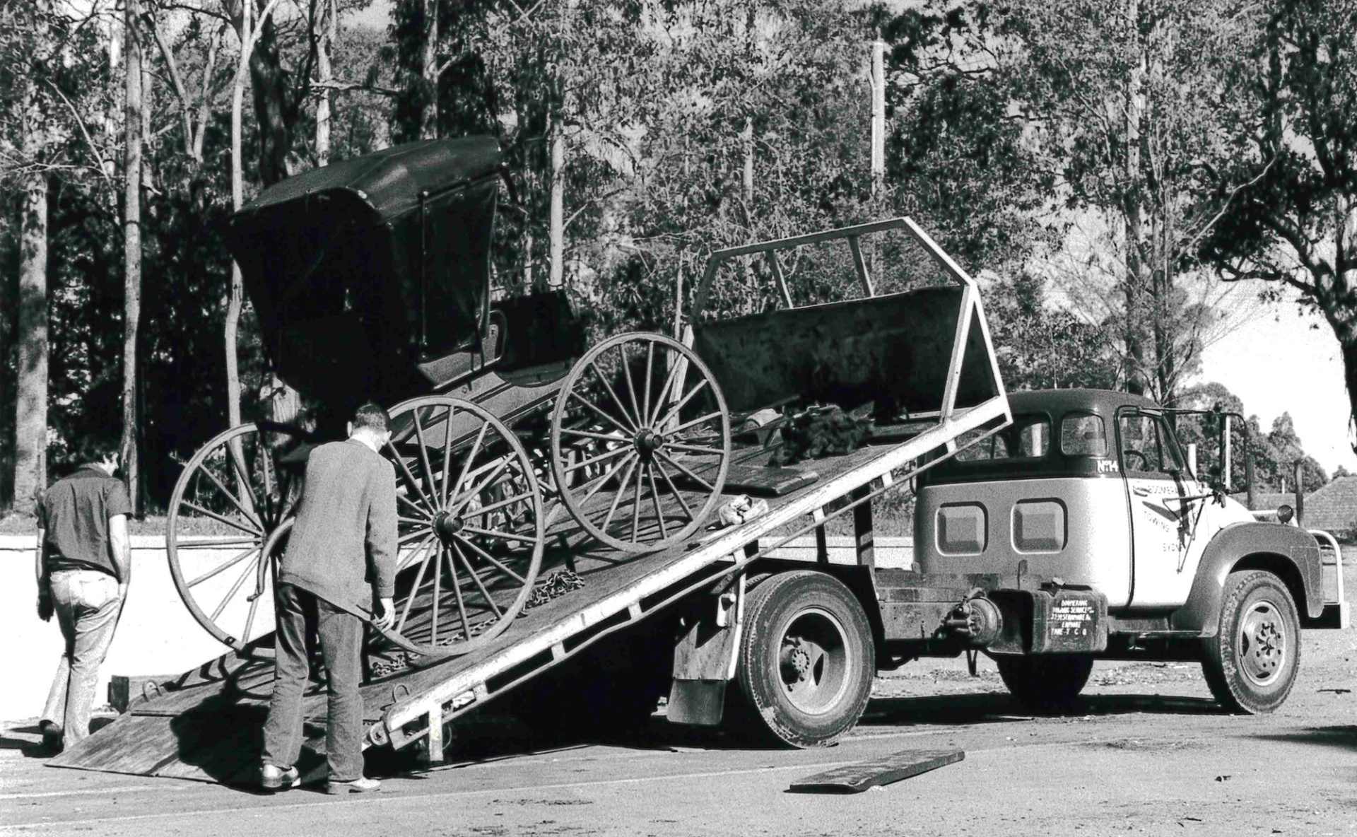 Black and white image of a buggy being unloaded off a flat bed