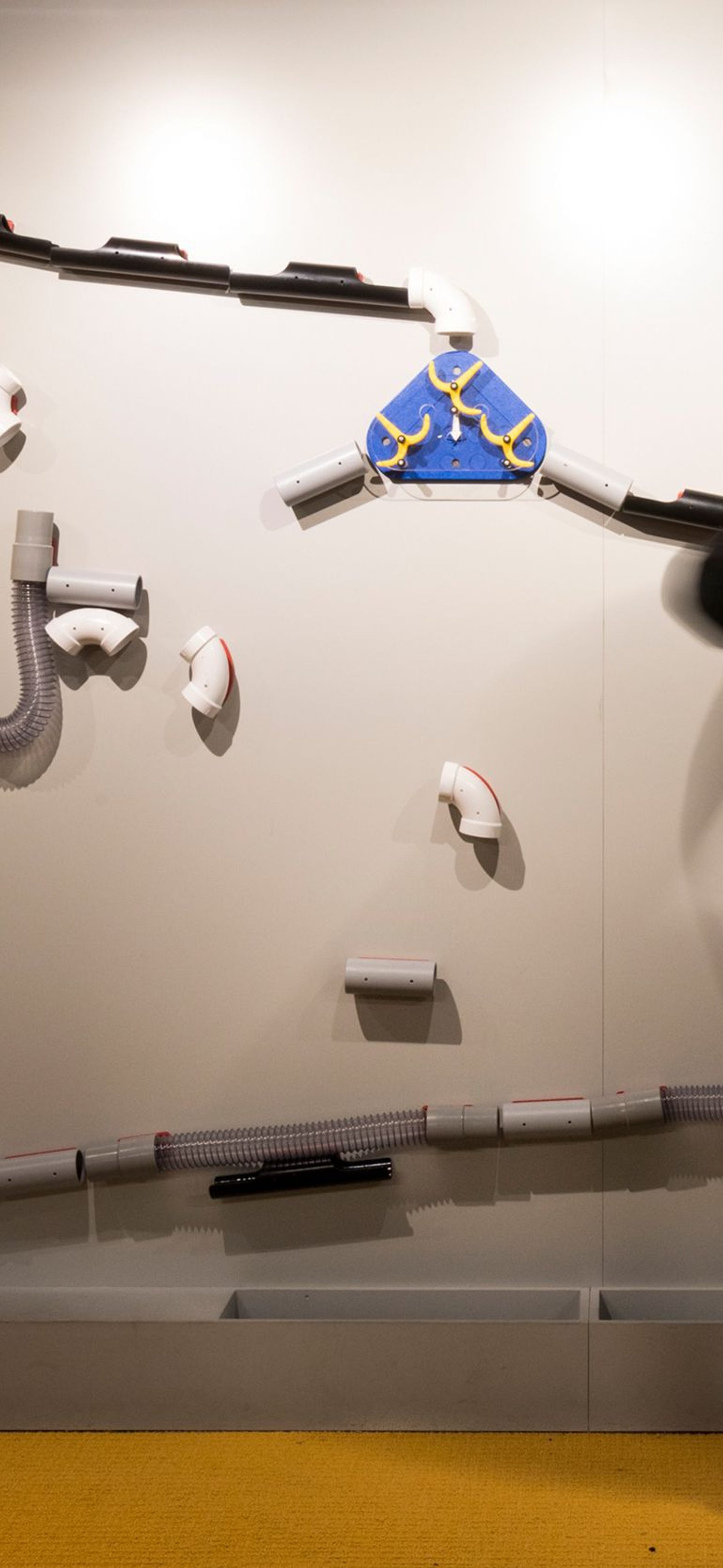 A man wearing all black is standing in front of a science based installation.