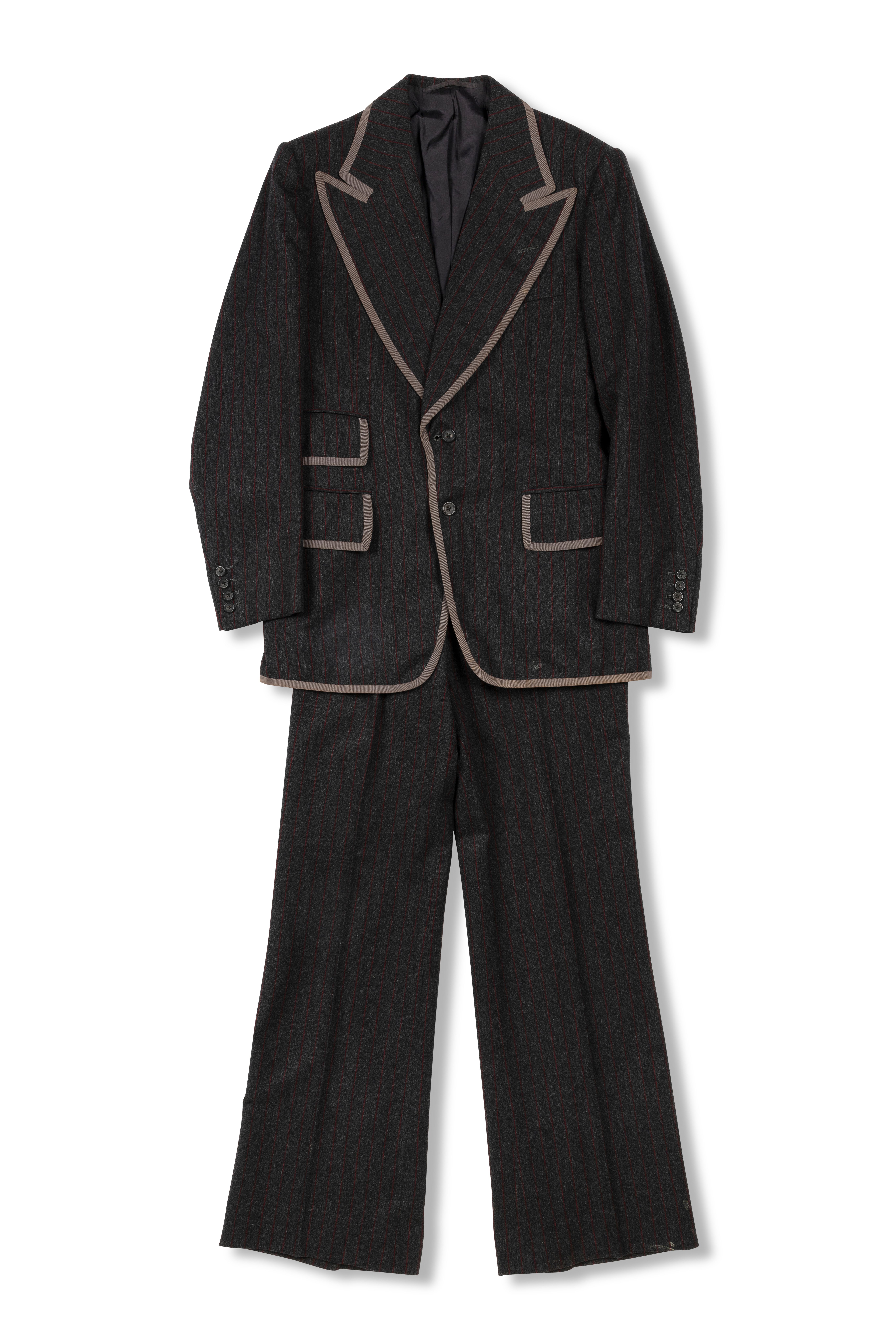 A dark brown mens suit of a blazer jacket and trousers made with wool and silk, the brim of the collar, pockets and sleeves are lined with a light brown fabric.