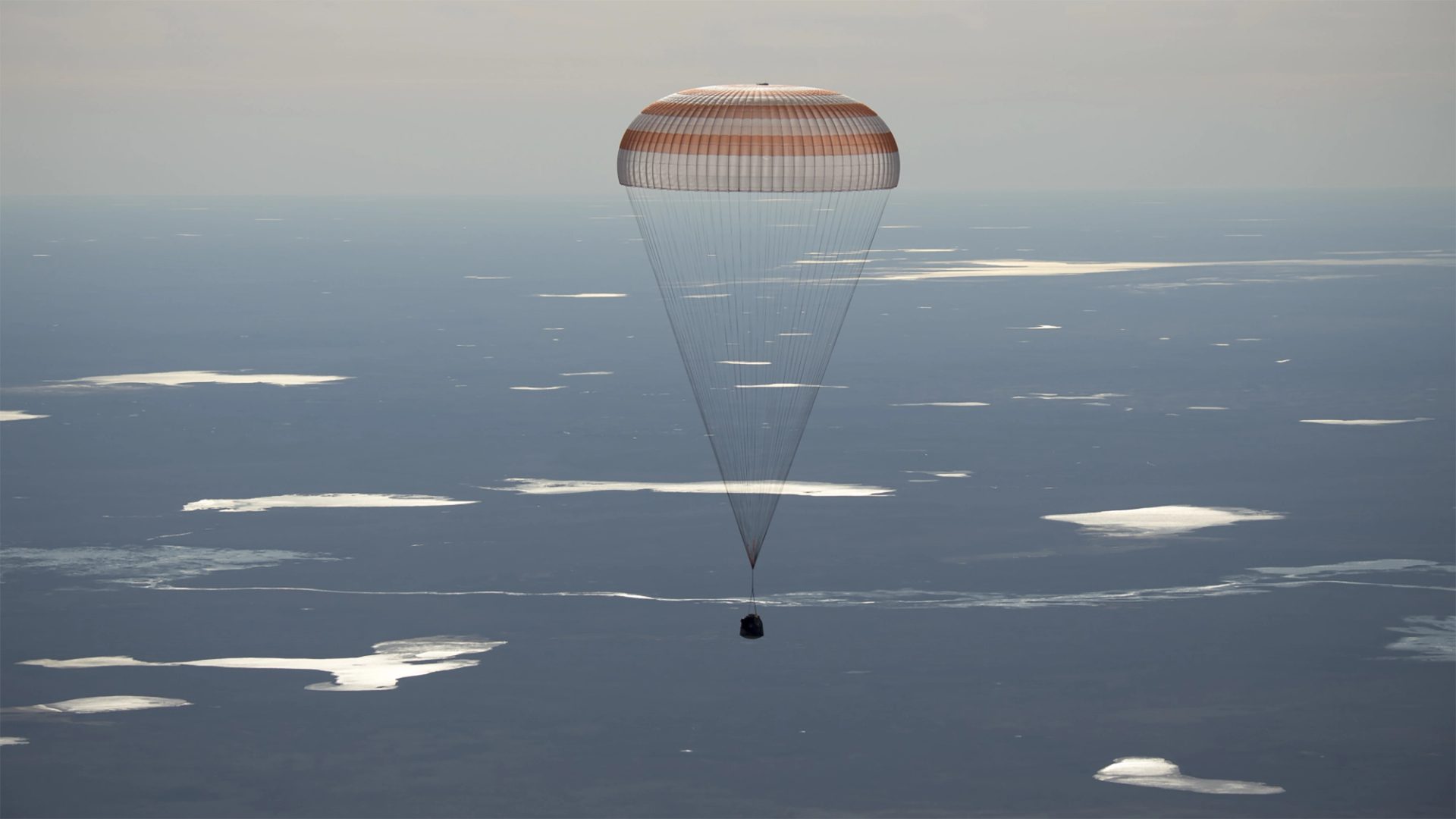 Image of the 50 Soyuz MS-02 landing, held by a parachute above the sky's atmosphere.