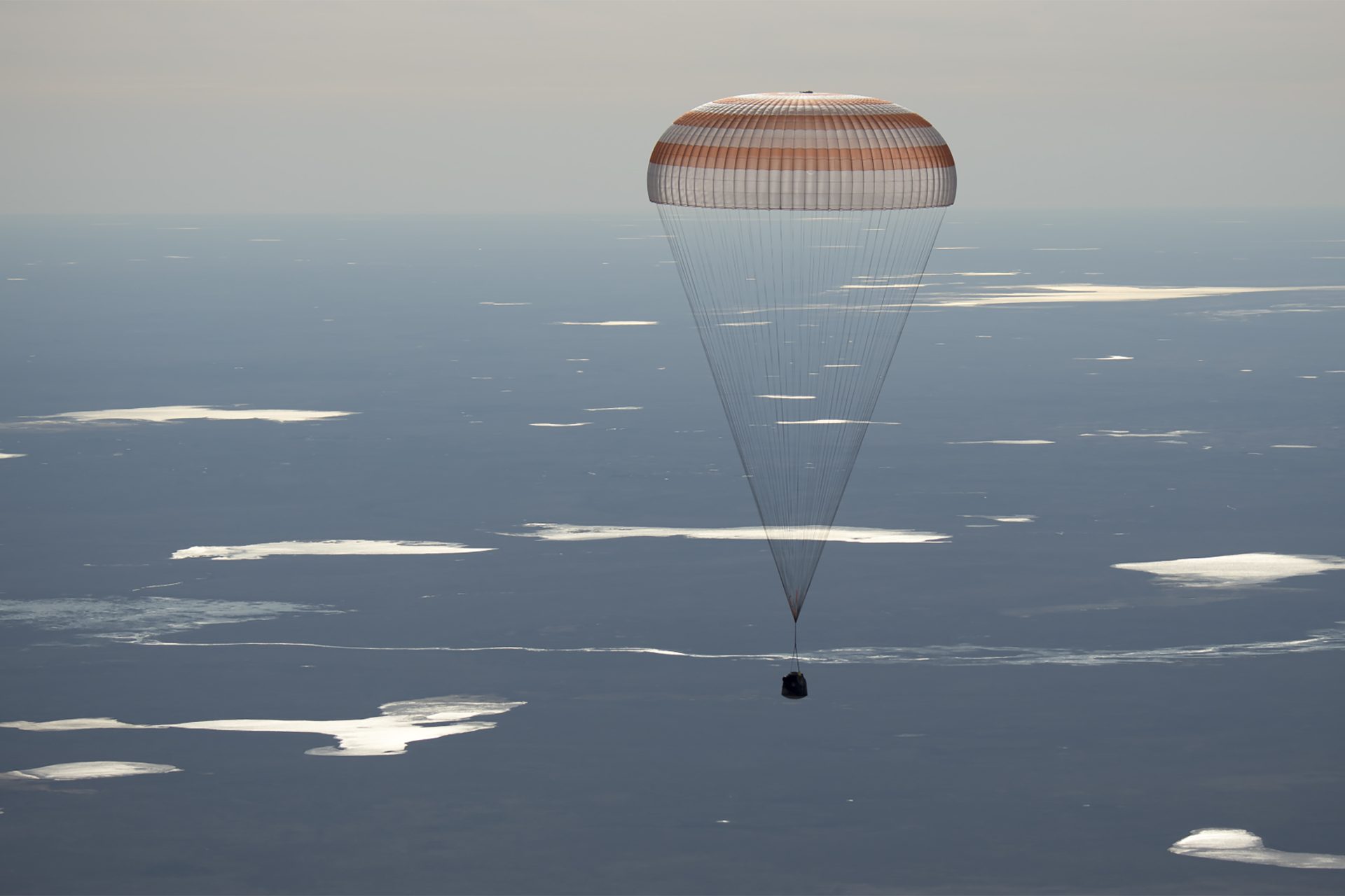 Image of the 50 Soyuz MS-02 landing, held by a parachute above the sky's atmosphere.
