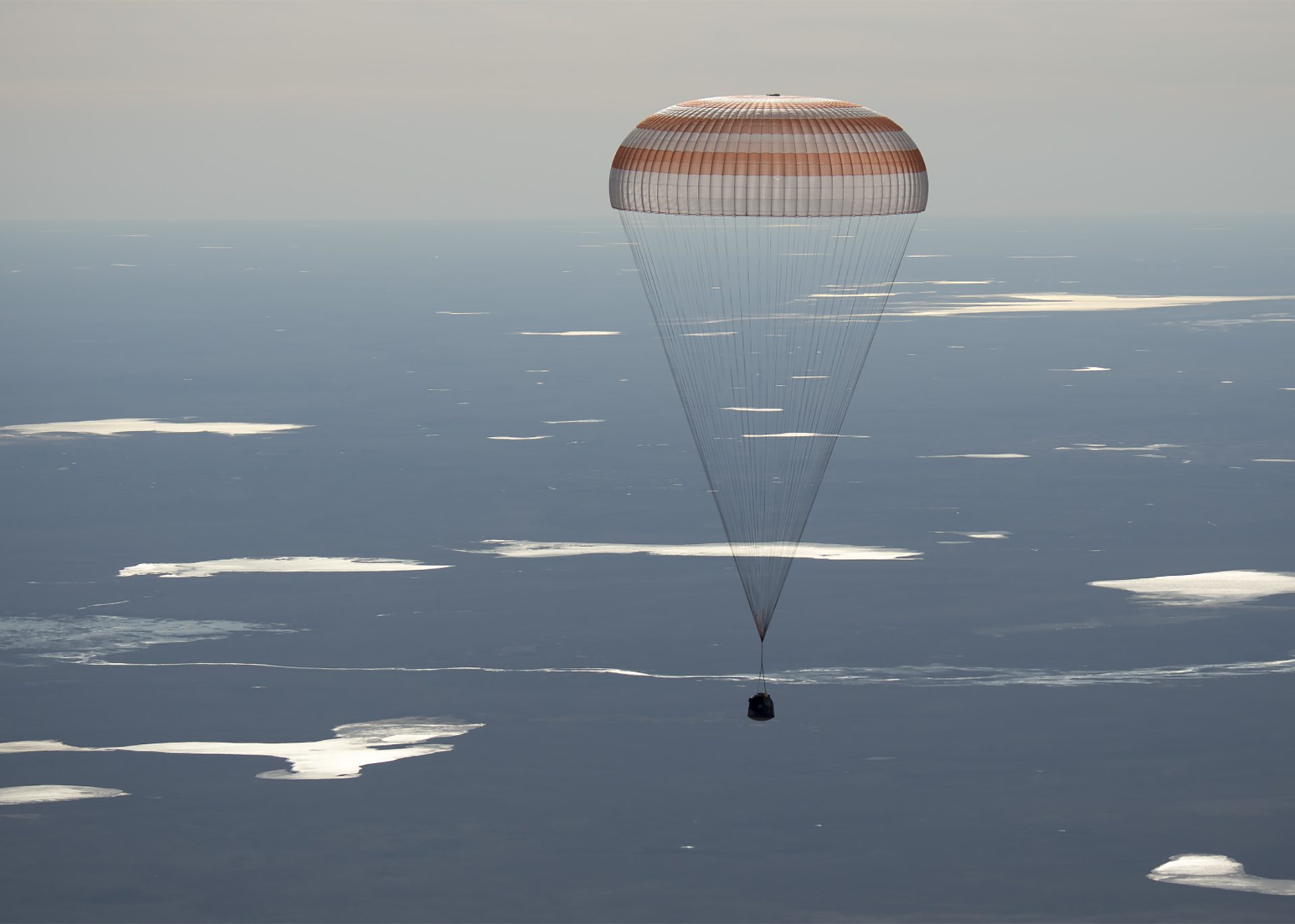 Image of the 50 Soyuz MS-02 landing, held by a parachute above the sky's atmosphere.