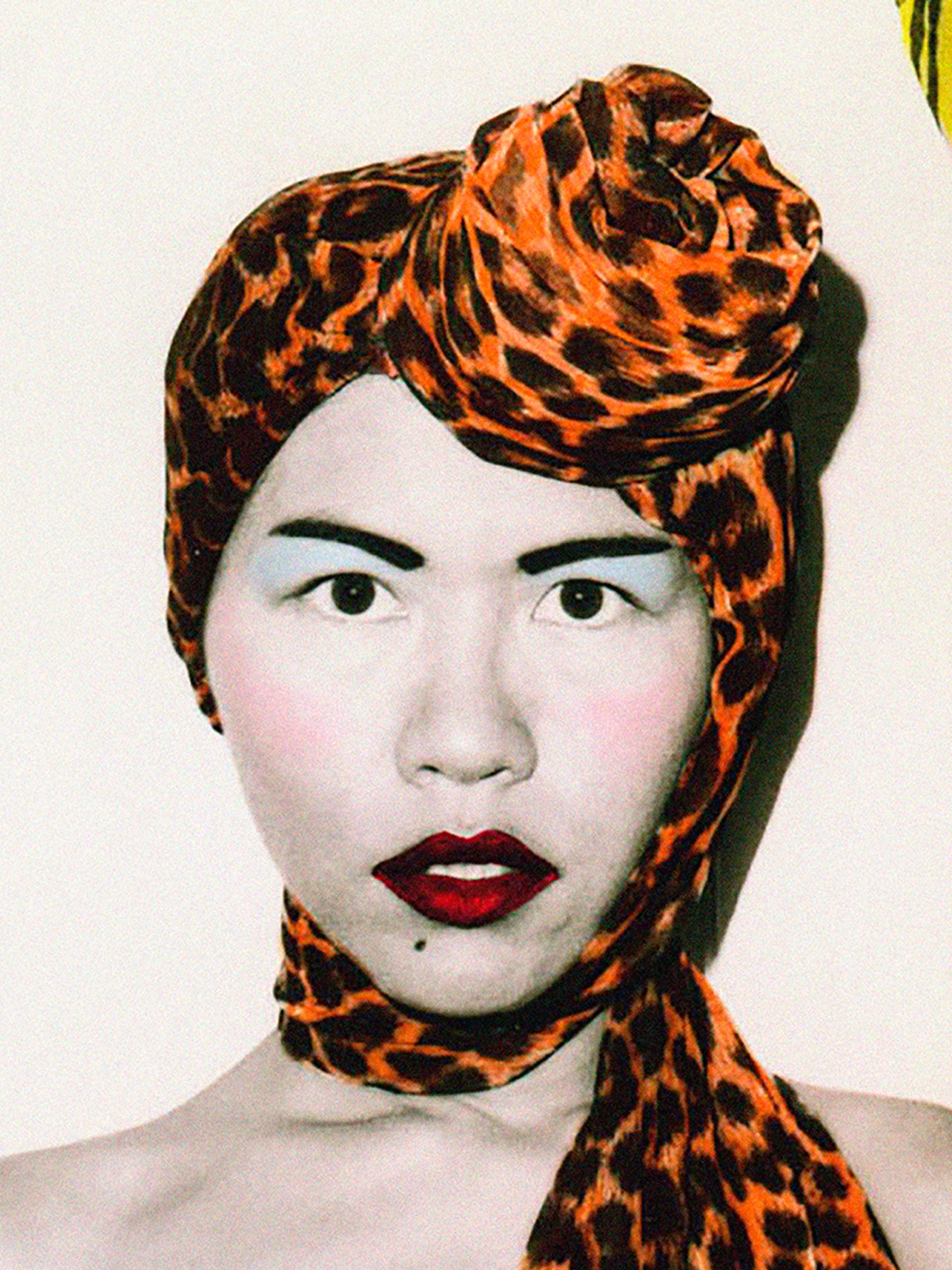 A photograph of fashion designers Jenny Lee and Linda Jackson. Both wear elaborate and highly colored headscarfs, along with a full face of carefully applied make-up.