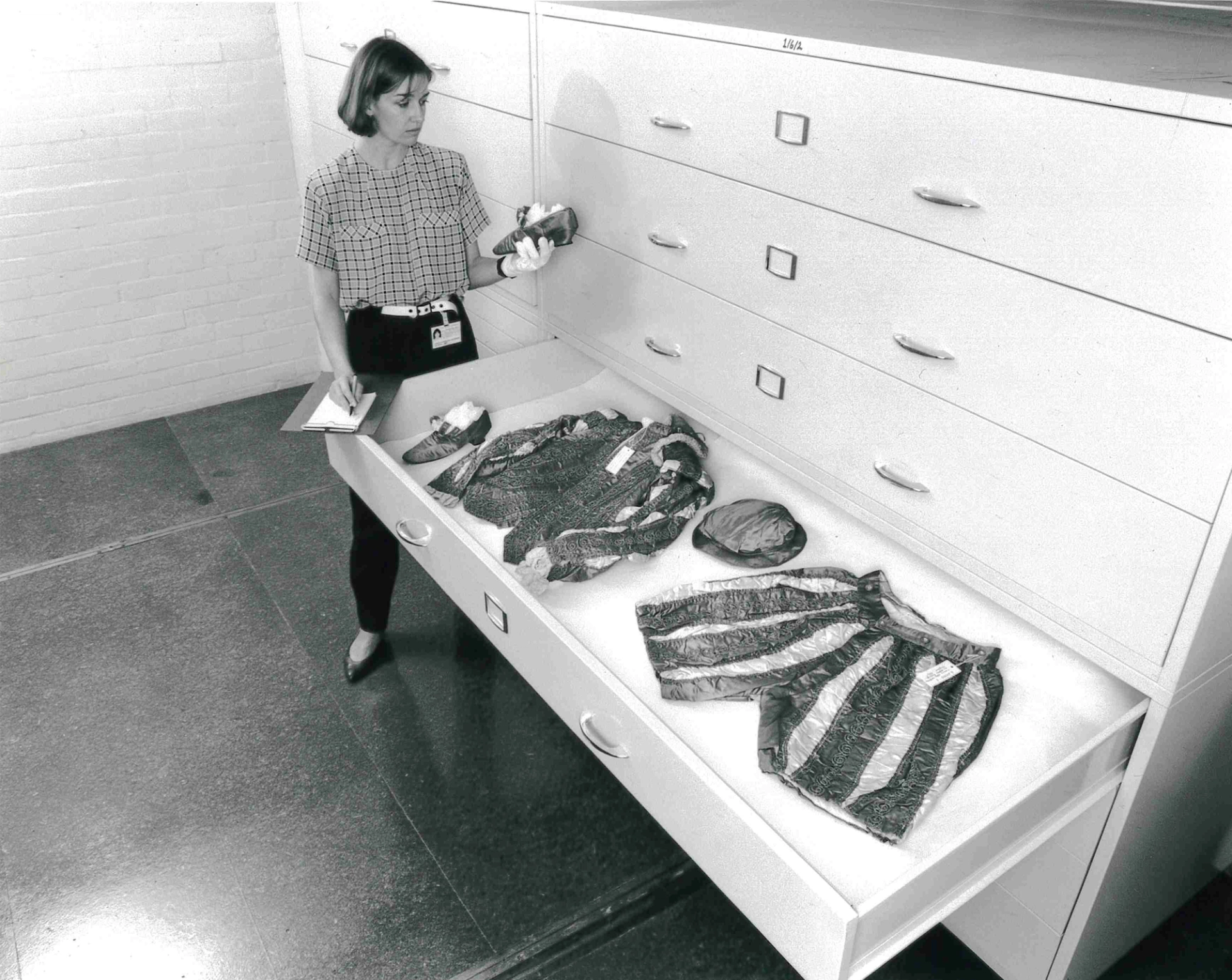 Black and white image of a museum employee opening storage drawers.
