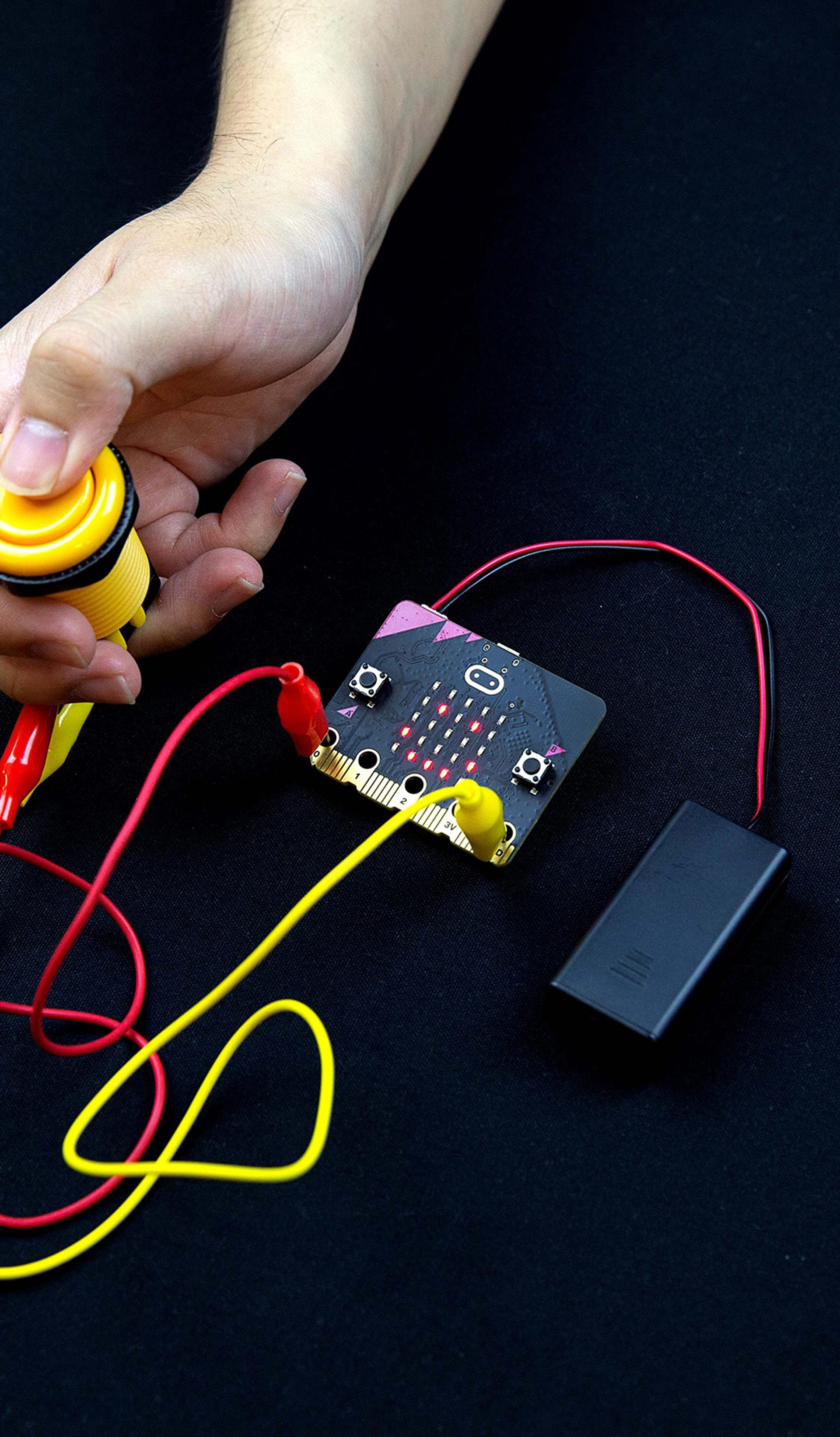 Micro:bit and button being pressed.