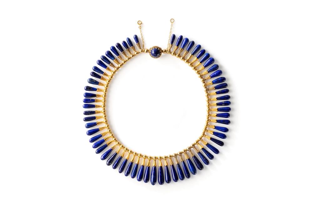 A matching necklace and earrings (pair) in a box, both have dark blue stones set in gold.