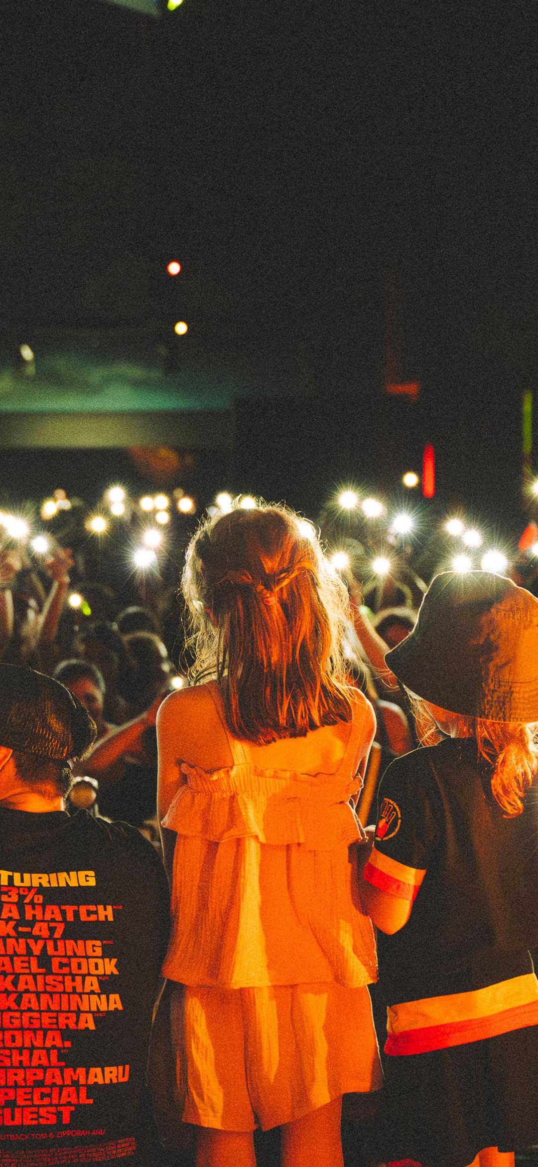 Crowd of people holding lights up towards the people on stage.