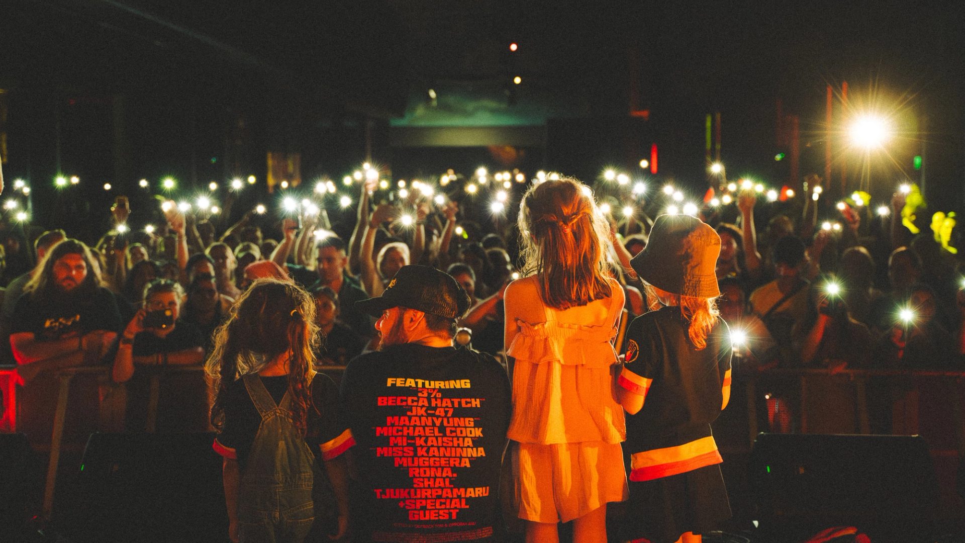 Crowd of people holding lights up towards the people on stage.