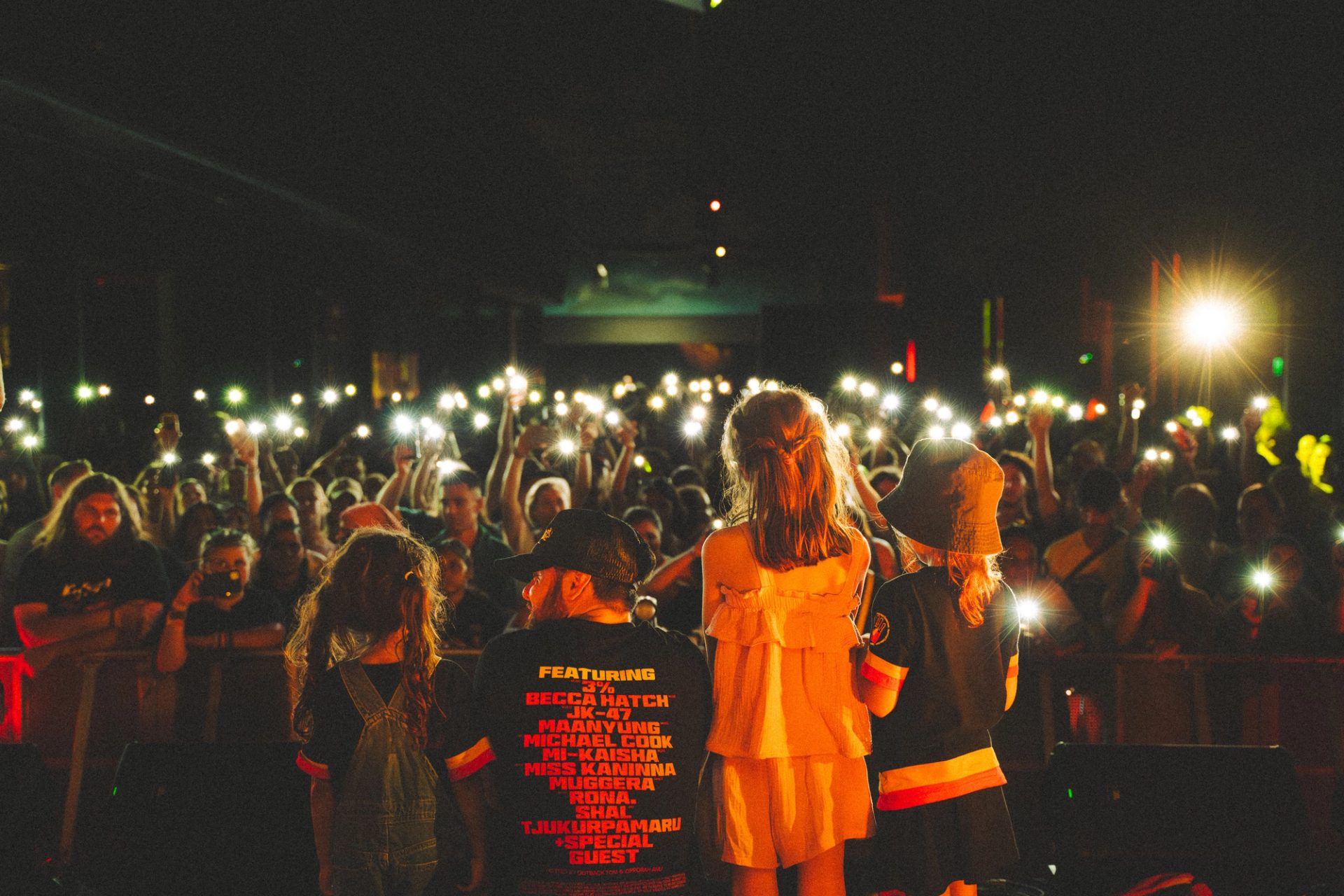 Crowd of people holding lights up towards the people on stage.