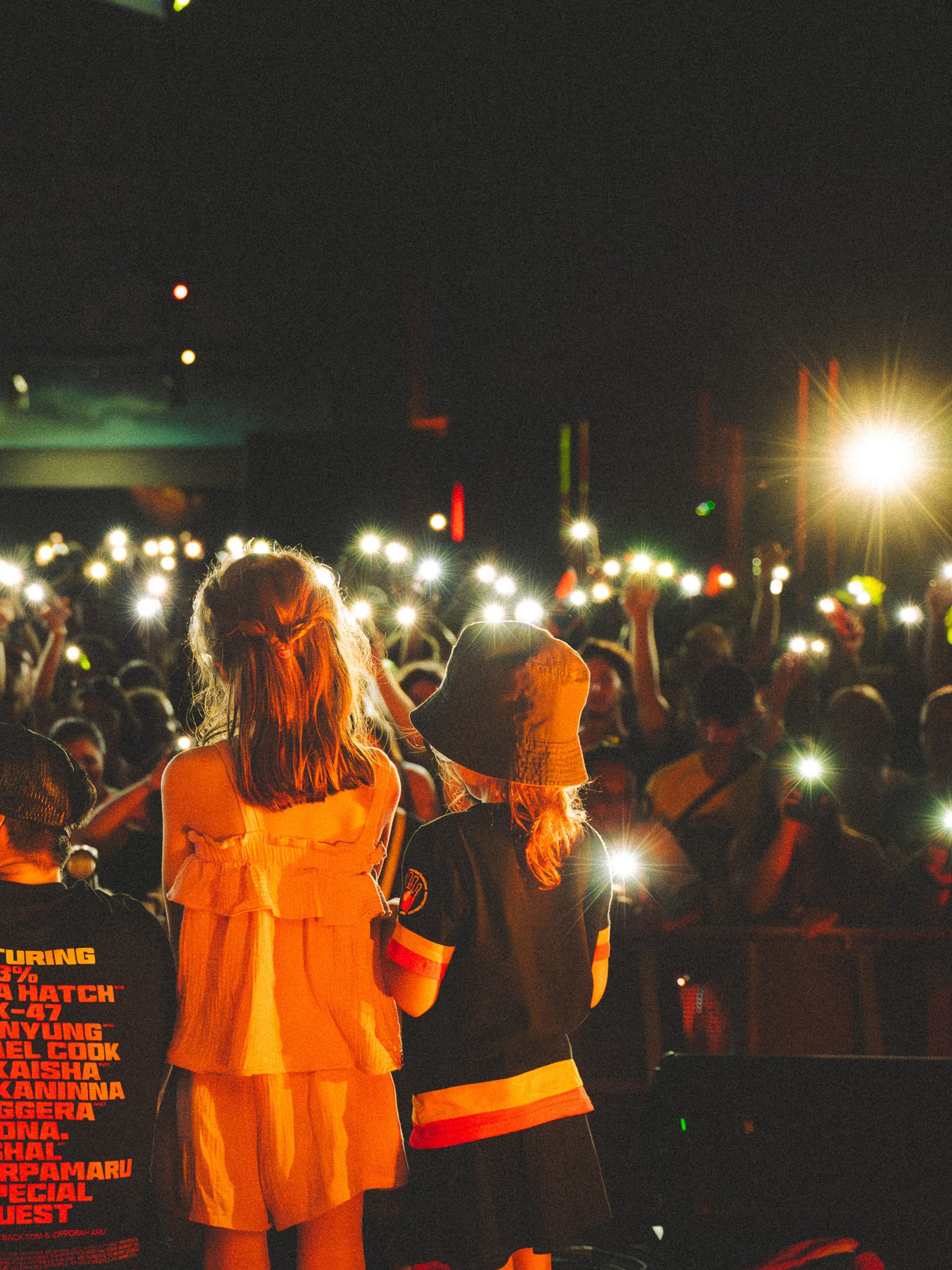 Crowd of people holding lights up towards the people on stage.