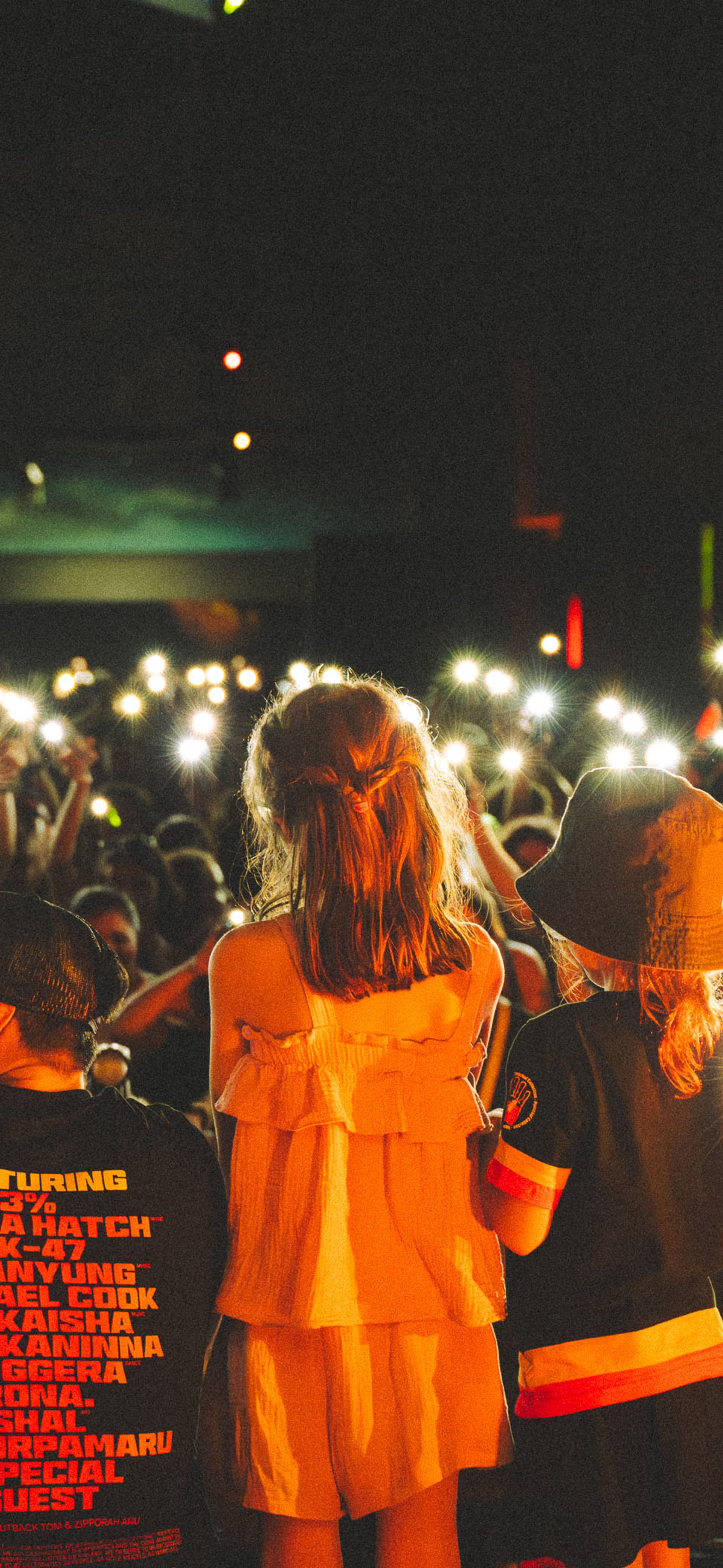 Crowd of people holding lights up towards the people on stage.