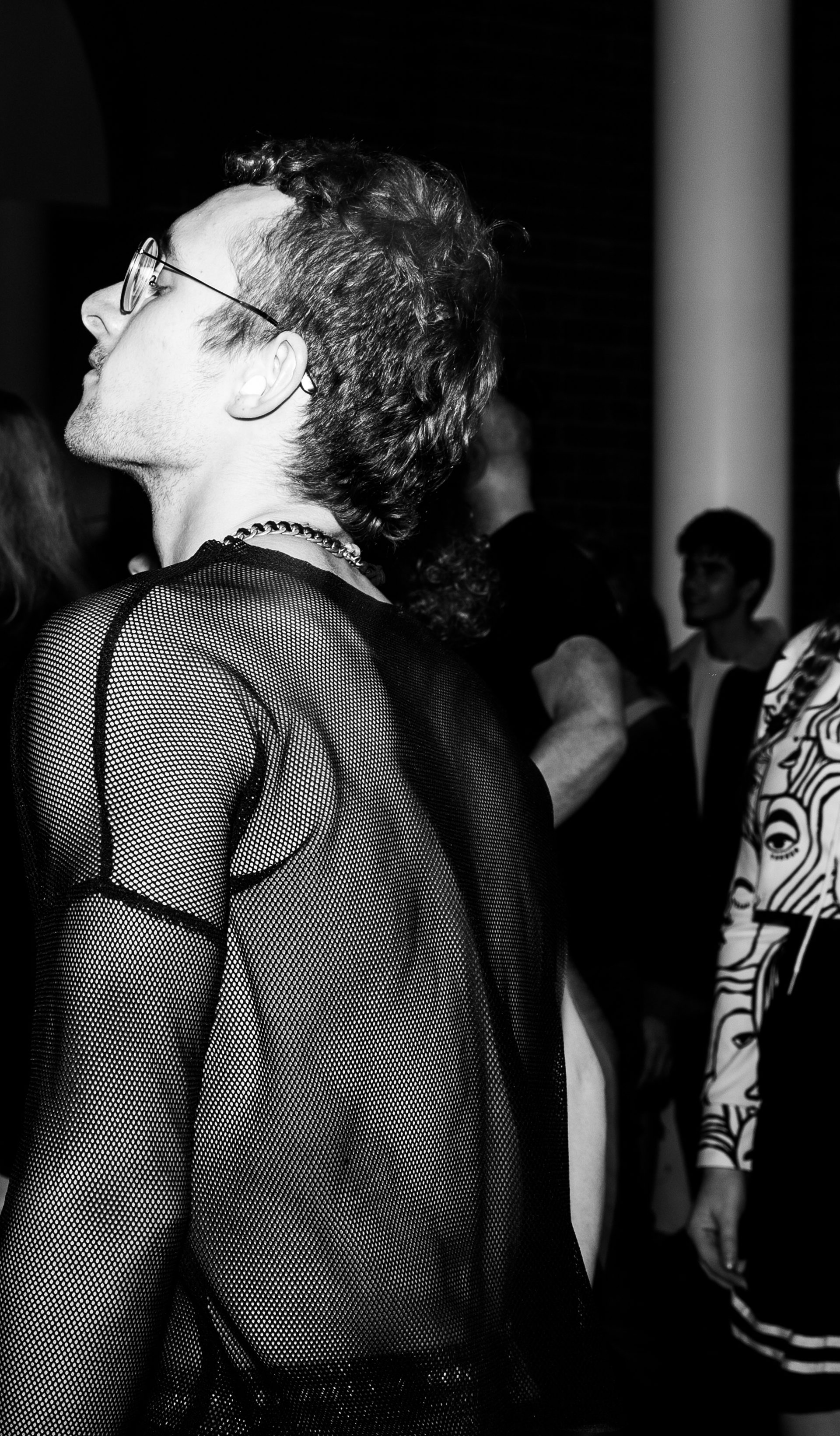 Black and white image of person in netted shirt in a crowd