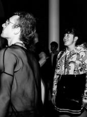 Black and white image of person in netted shirt in a crowd