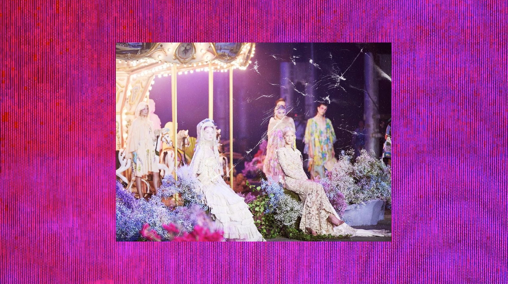 Models pose on the runway during the Australian Fashion Week 2022 Romance Was Born runway show in the center frame. They are wearing colourful floor length dresses. There is a pink LED screen background.