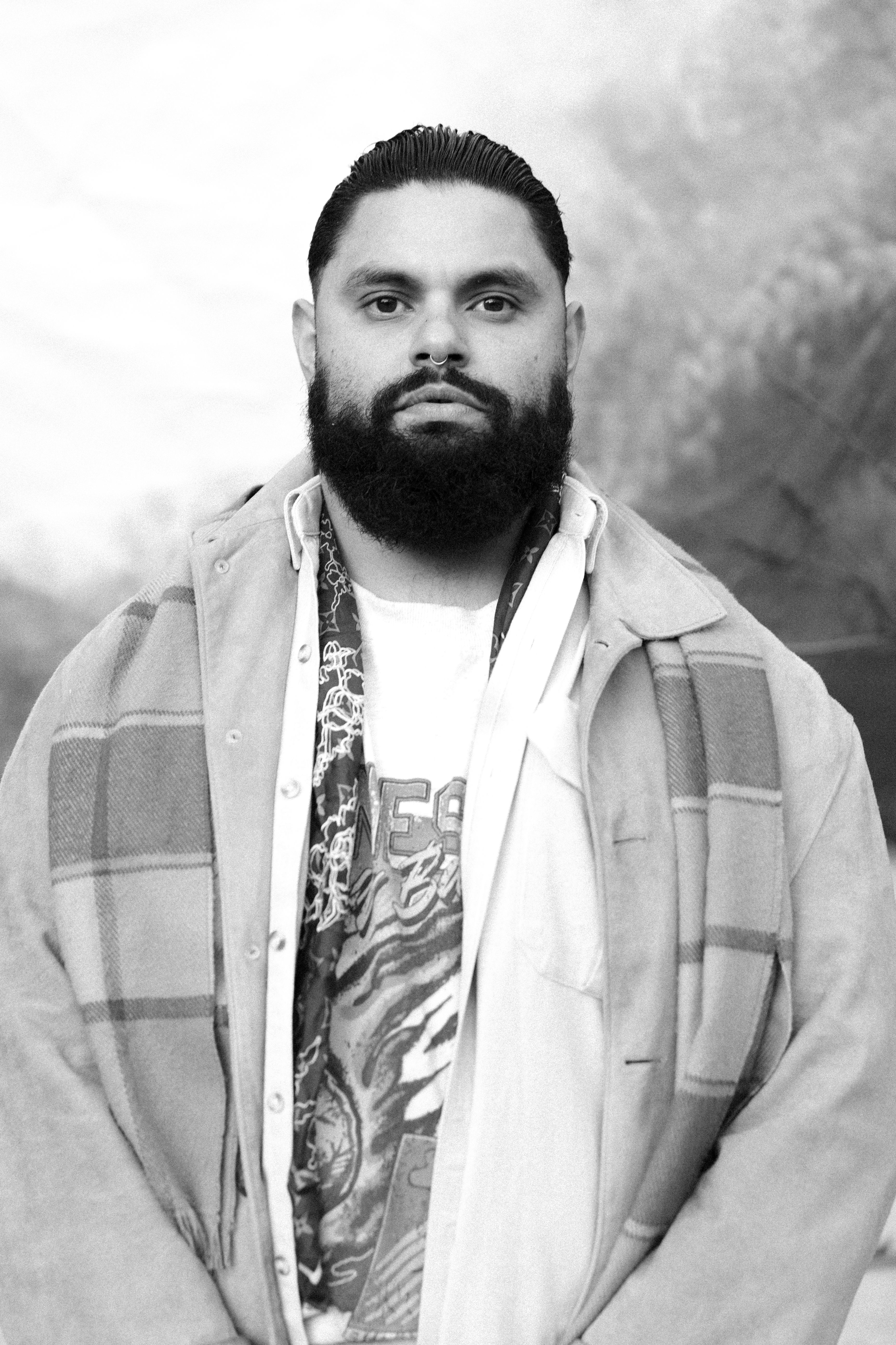 A Wiradjuri Gamillaraay man stands in front of a painted backdrop.