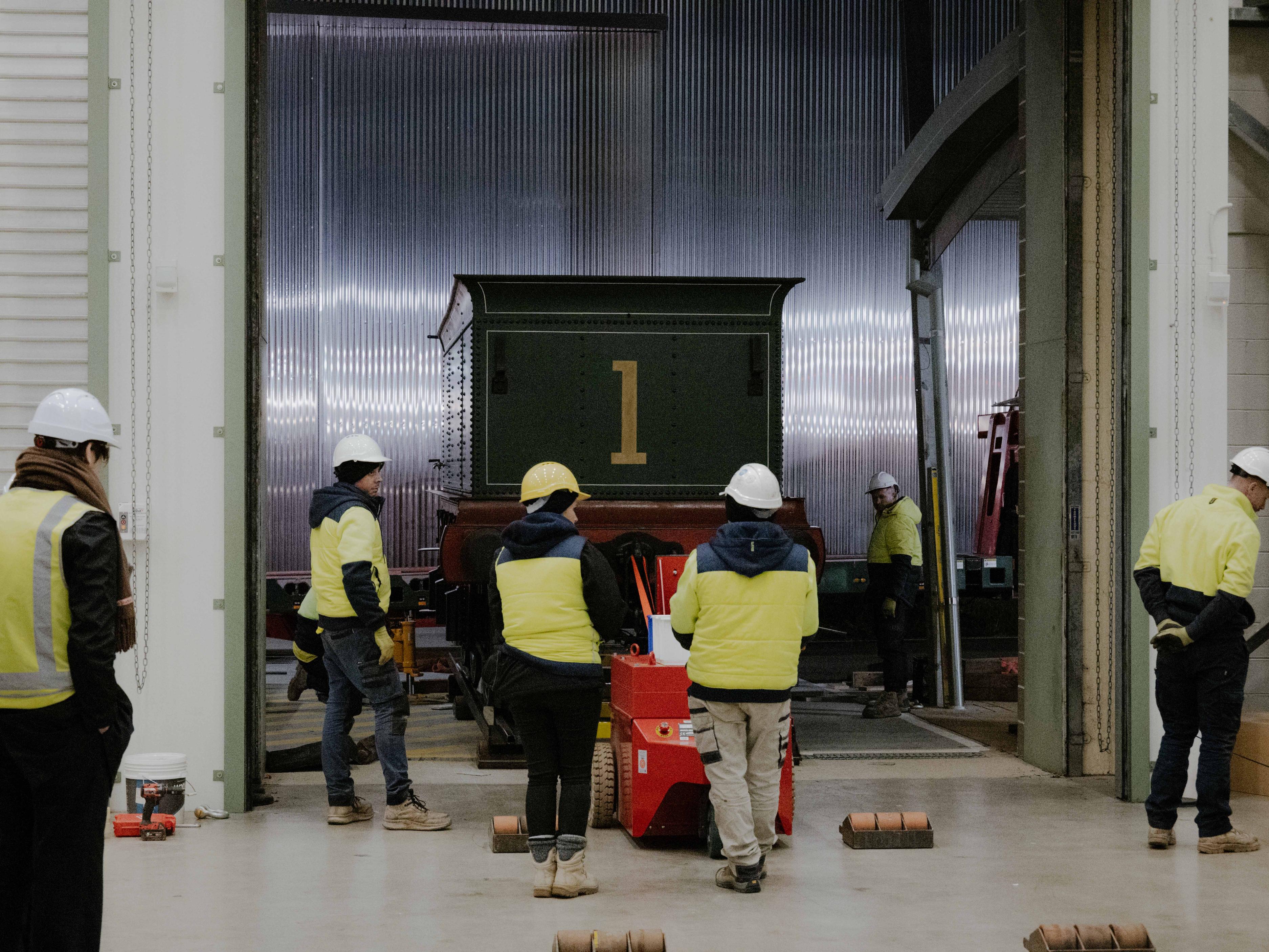 Trades people working around a train carriage.