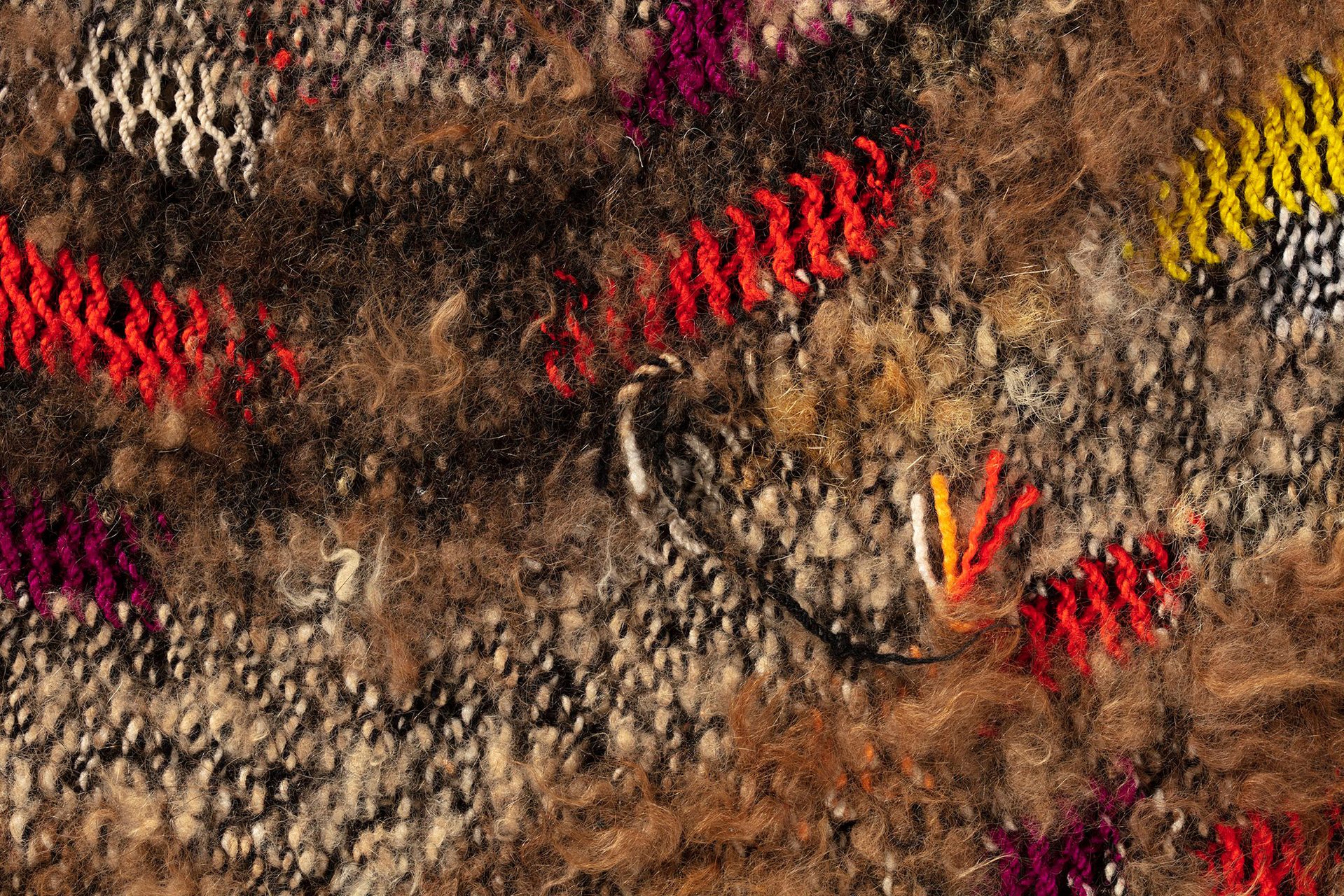 A hand woven polyester fibre and wool bag featuring colourful patterns.