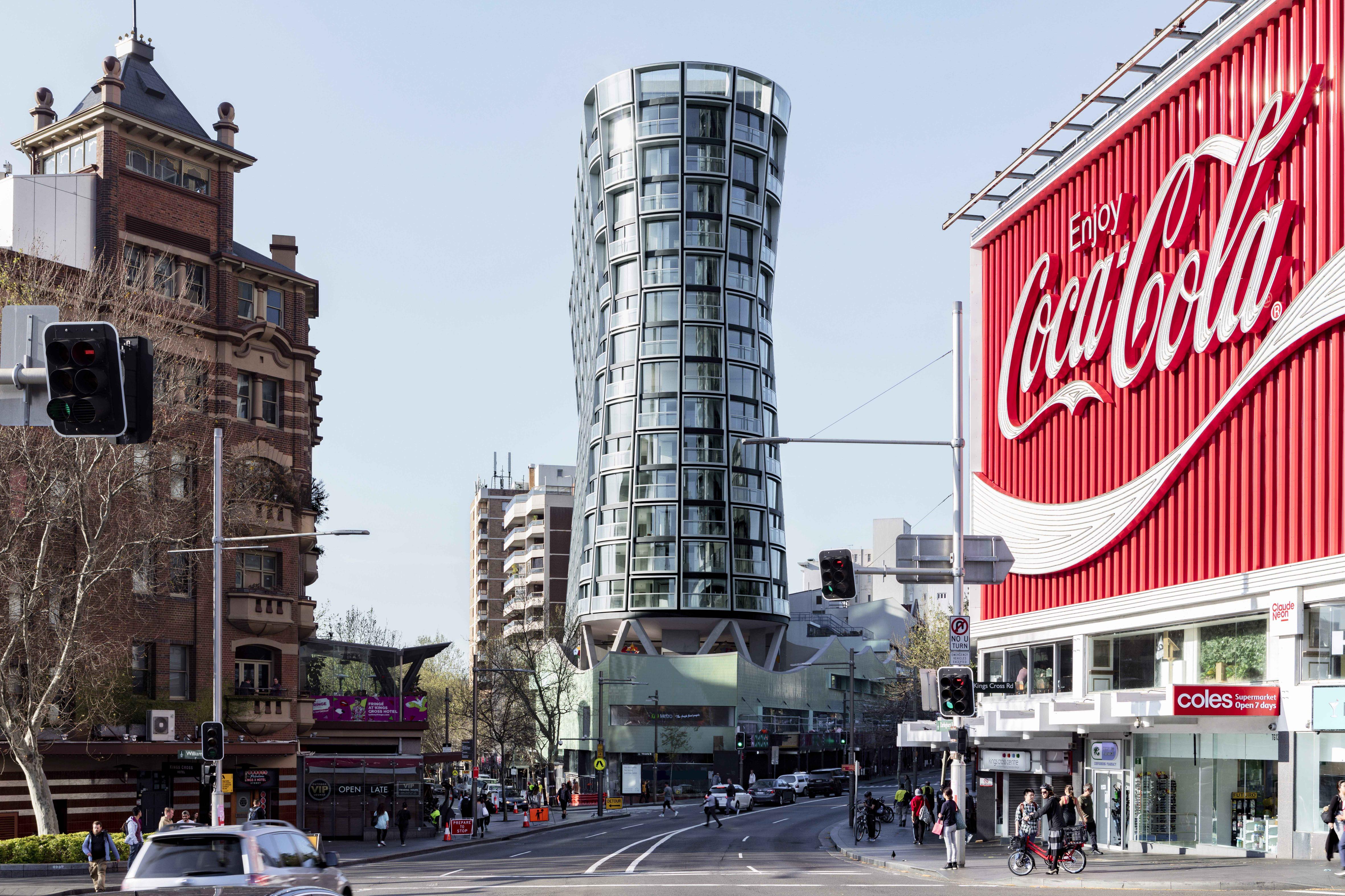 A tall curvaceous building standing amongst a city scape.