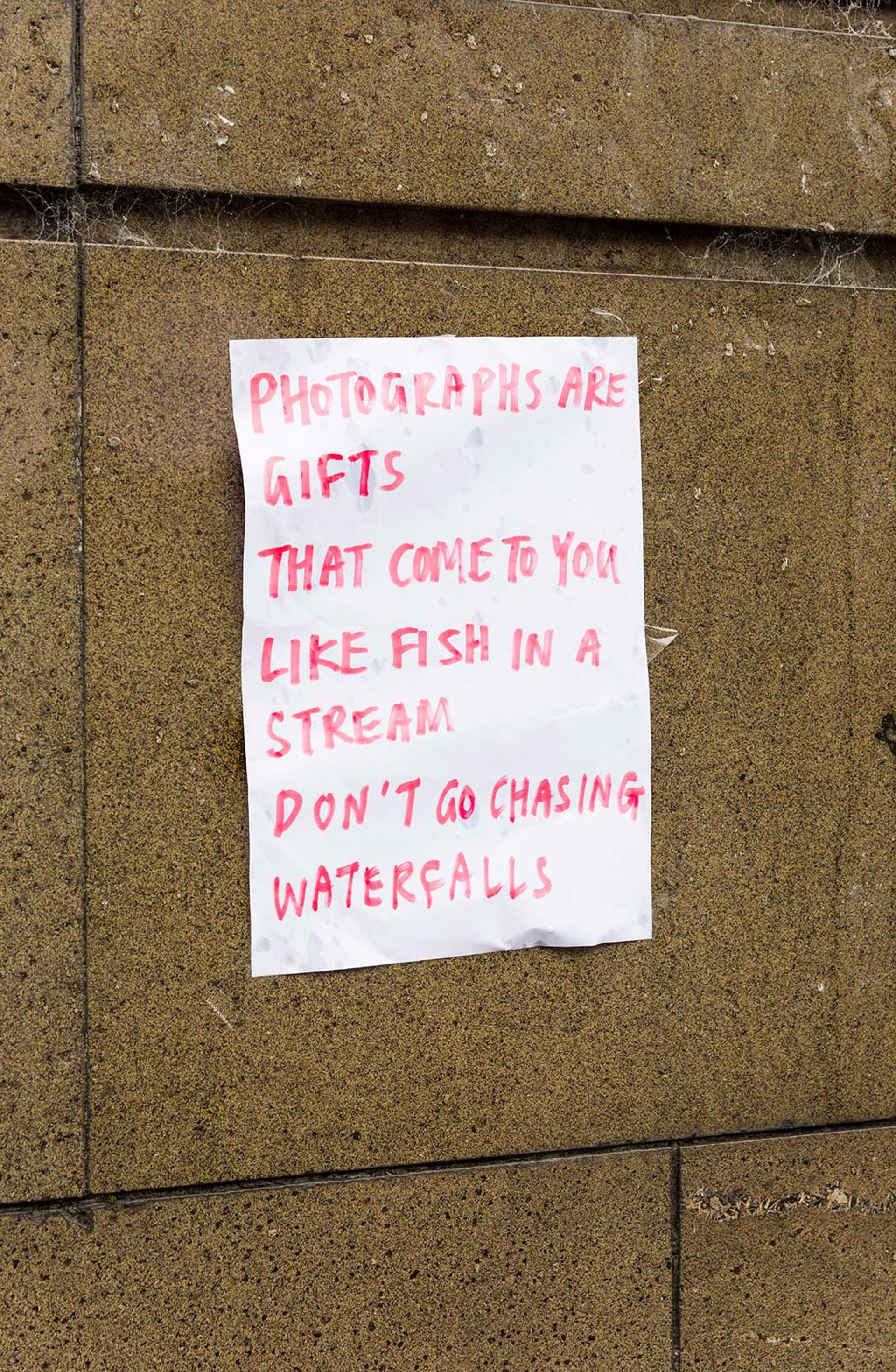 Note reading “PHOTOGRAPHS ARE GIFTS THAT COME TO YOU LIKE FISH IN A STREAM DON’T GO CHASING WATERFALLS”