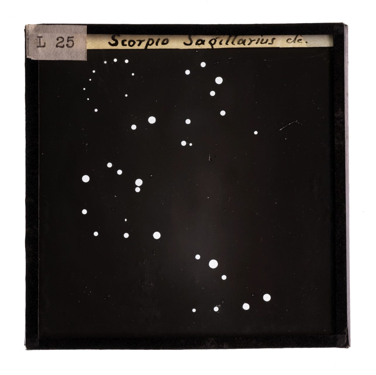 Glass plate slide of constellations Scorpio and Sagittarus, a black night sky with white dots to indicate the mapping of the constellations.