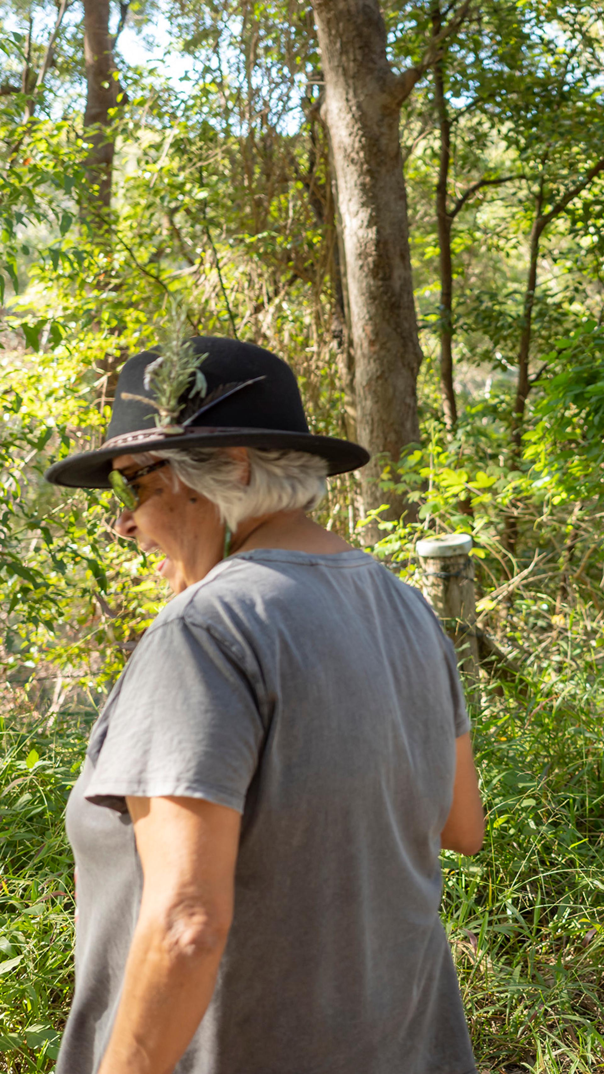 Two women standing outside in a green, leafy environment.