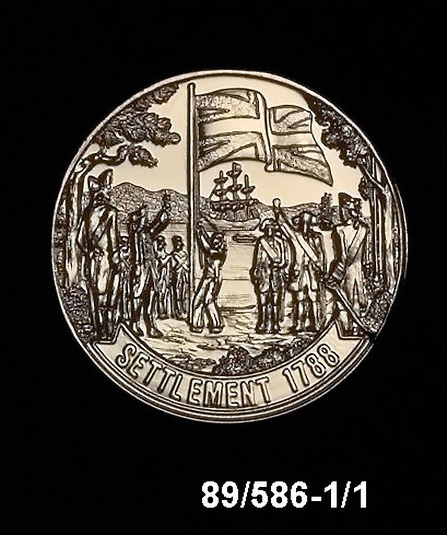 A medal featuring engraved images of colonists hoisting a British flag. A large ship is in the background.