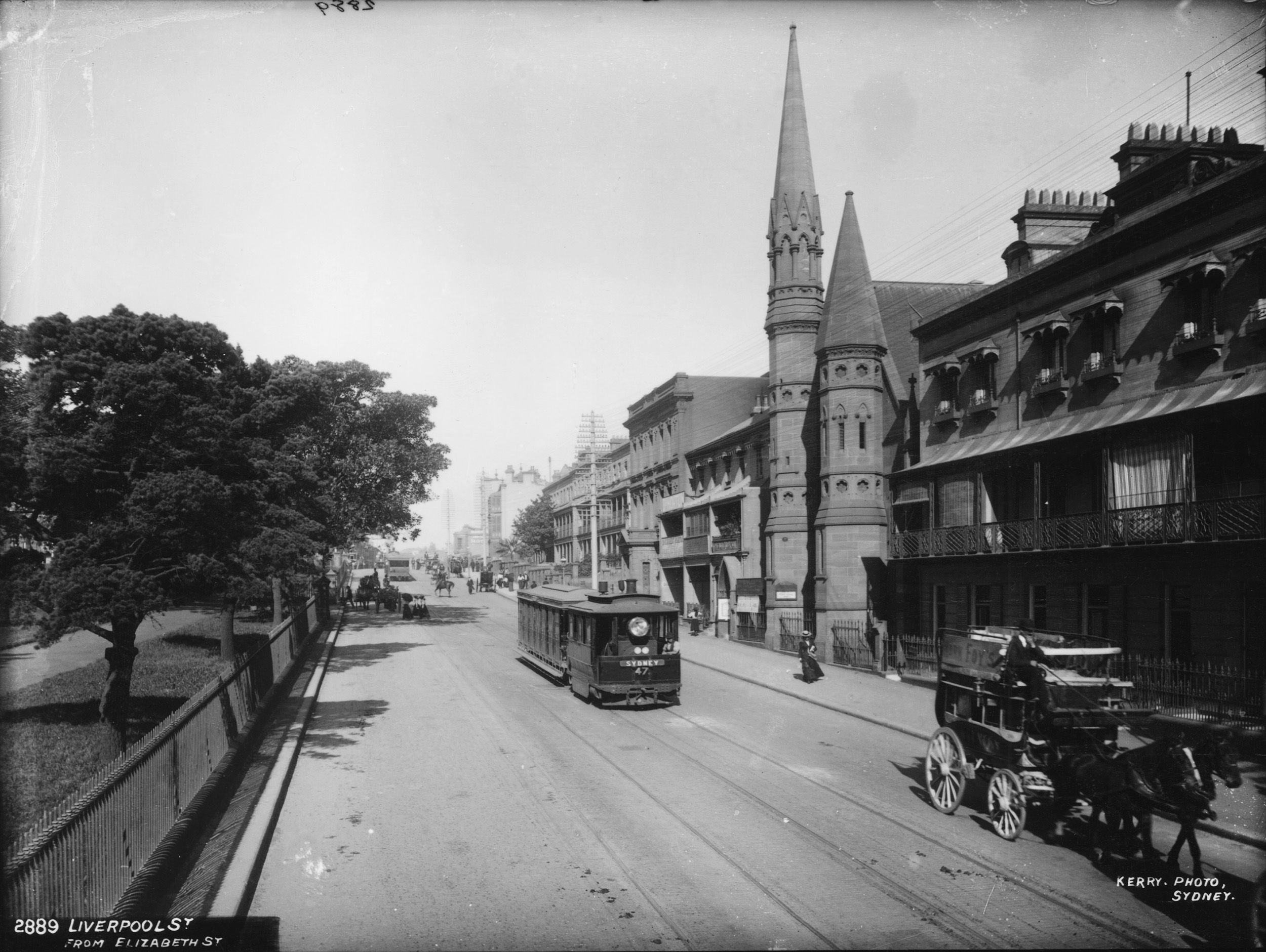 Black and white photograph of a steam tram travelling down a Sydney street