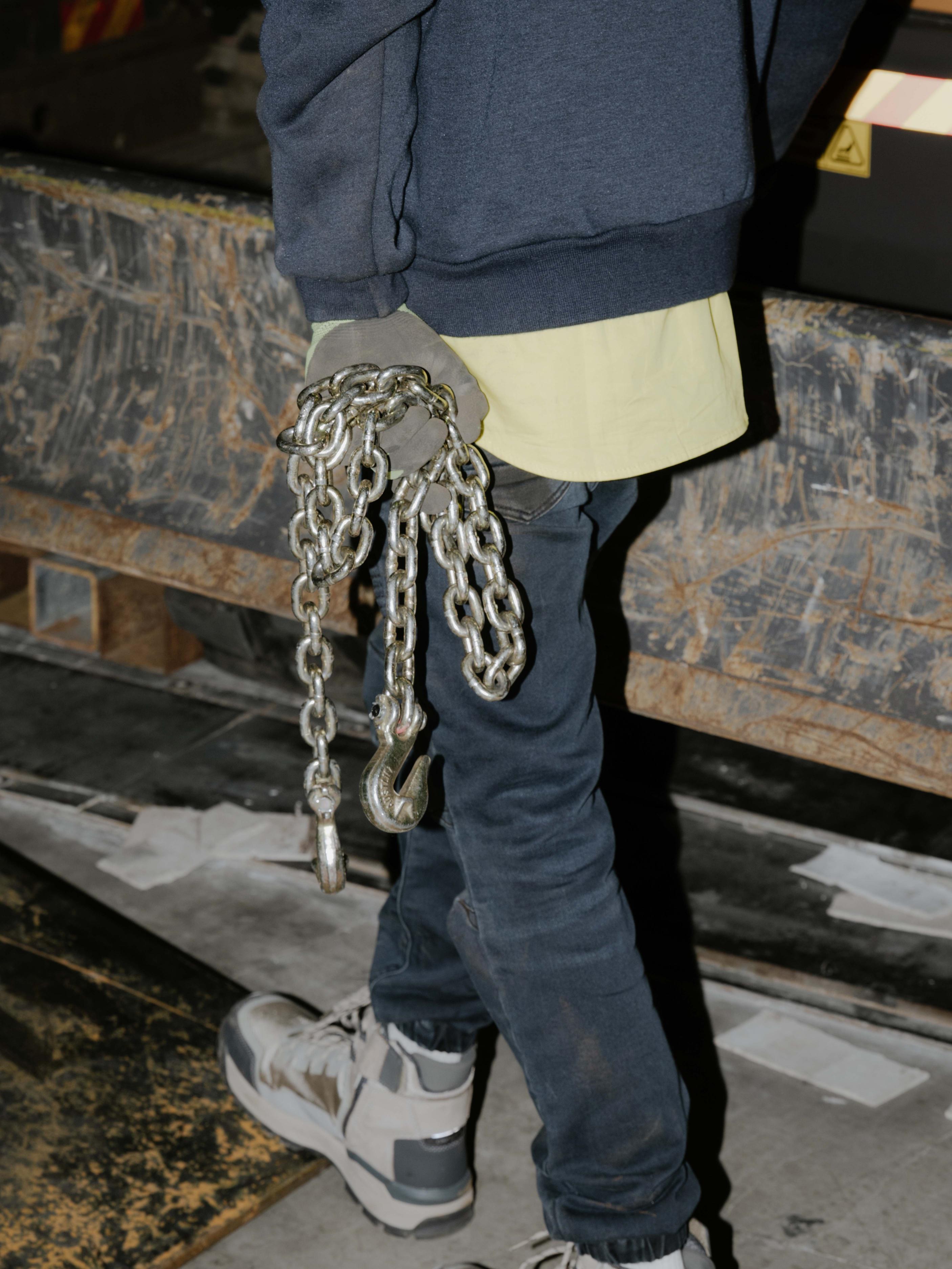 Bottom half of a trades person carrying chains.