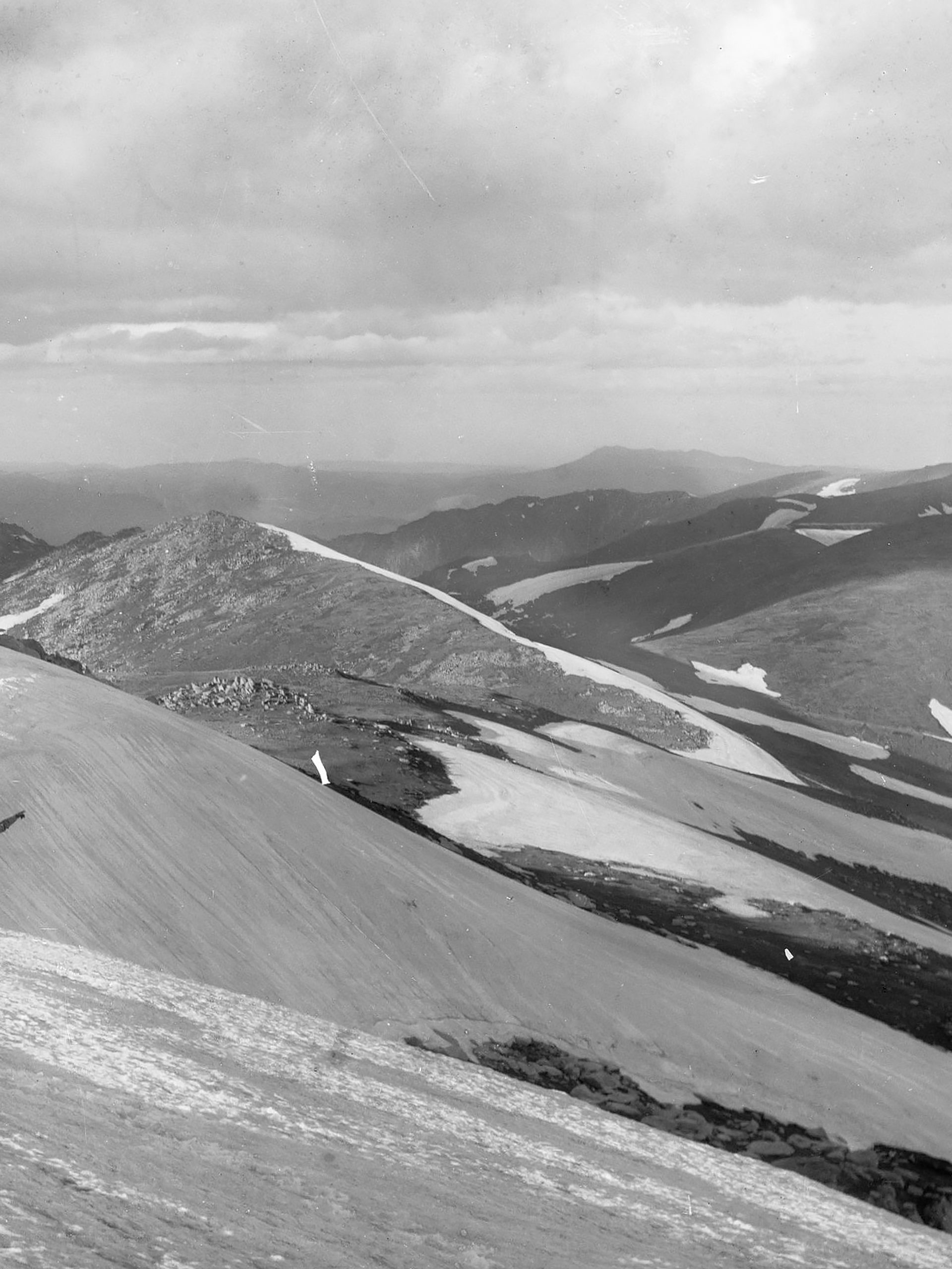 Far away humans in the snow mountains pointing away from camera