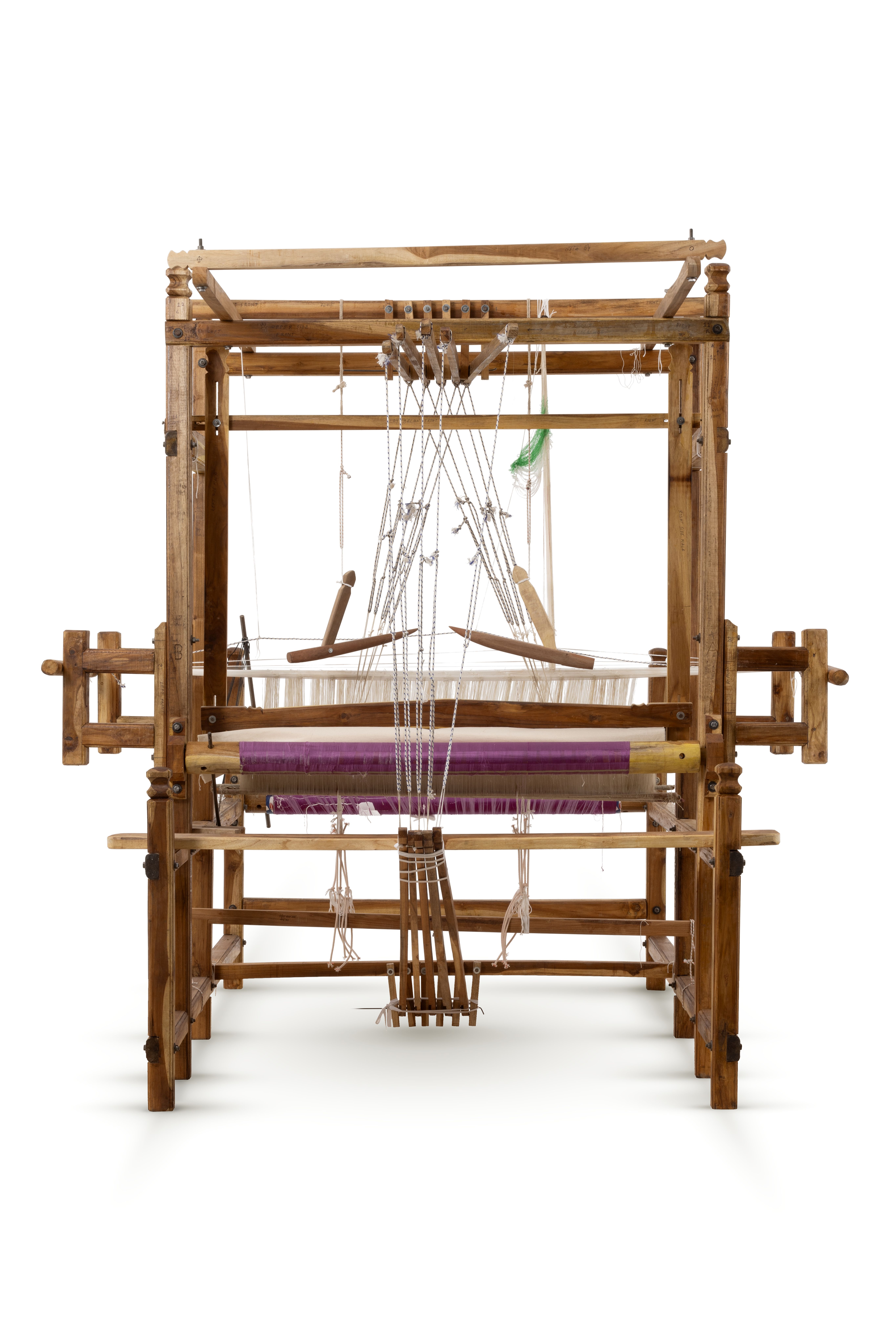 A sturdy wooden frame loom with five pedals. The loom has been warped with purple silk which is partially woven in stripes with the same purple silk and gold thread. The cloth is patterned with a repeating diamond motif in gold on purple and purple on gold.
