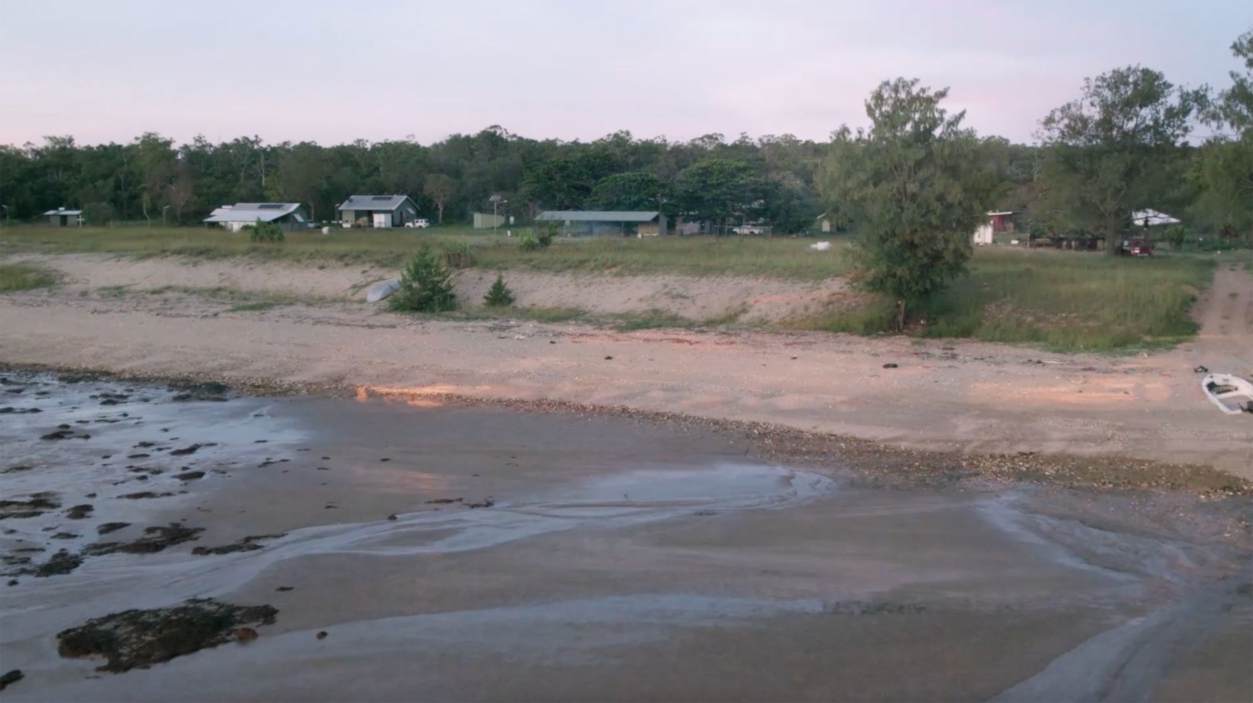 Laŋarra from afar, beach and sand, with houses in the background.
