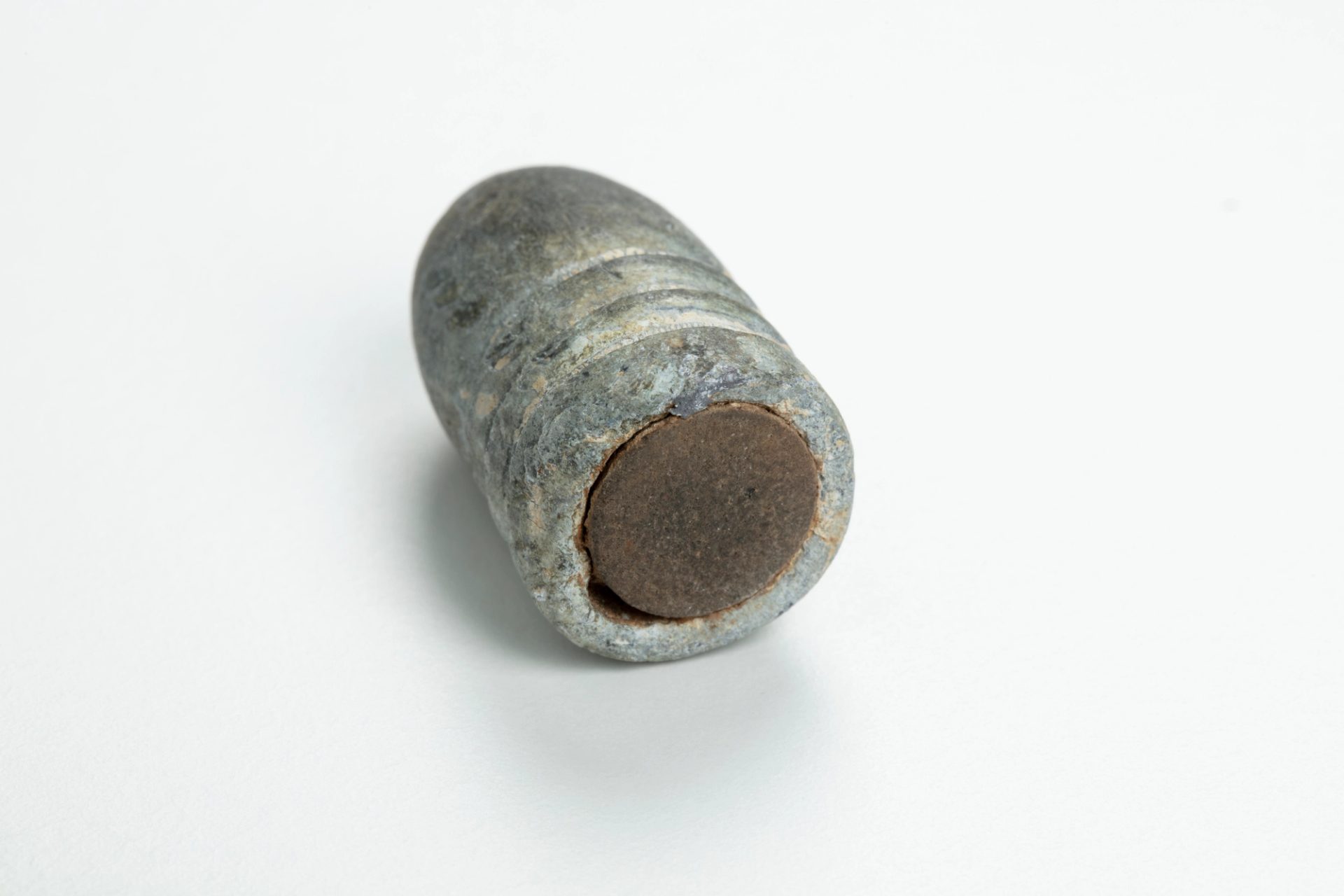 Cylindrical bullet cartridge with smooth dome at end and three ridges near base.