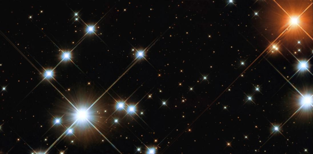 Several very bright, pale blue super-giant stars, a solitary ruby-red super-giant, and a variety of other brilliantly coloured stars are visible in the image, as well as many much fainter ones, often with intriguing colours.