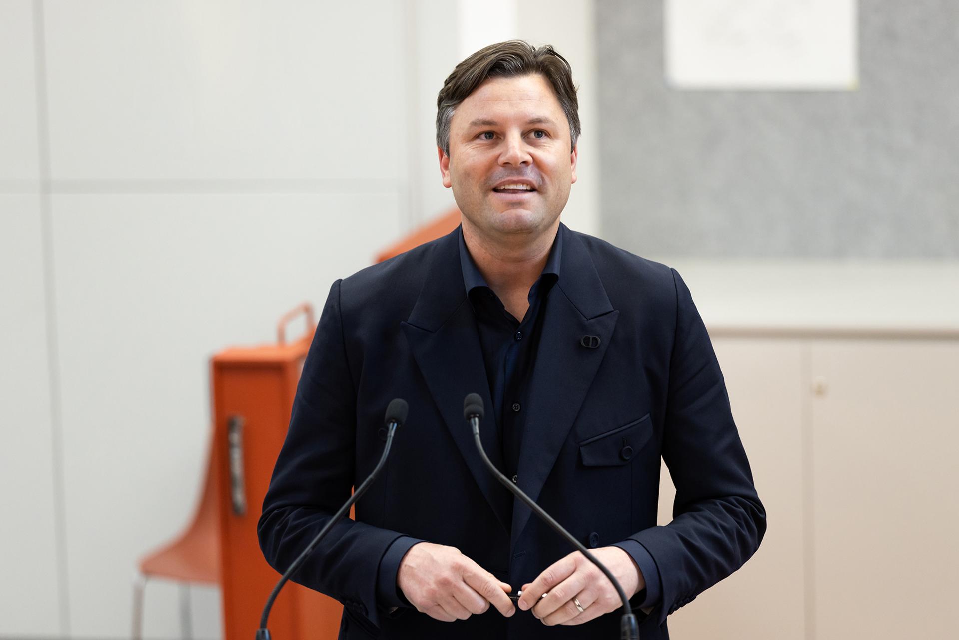 Man presenting at podium with two microphones.