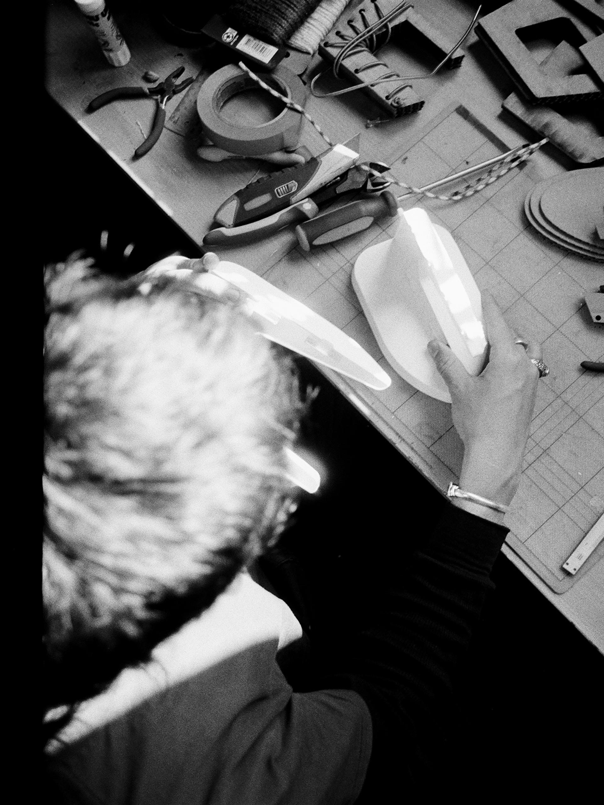 Two film images side by side – an overhead view of Ben Styles working on a product at a desk.