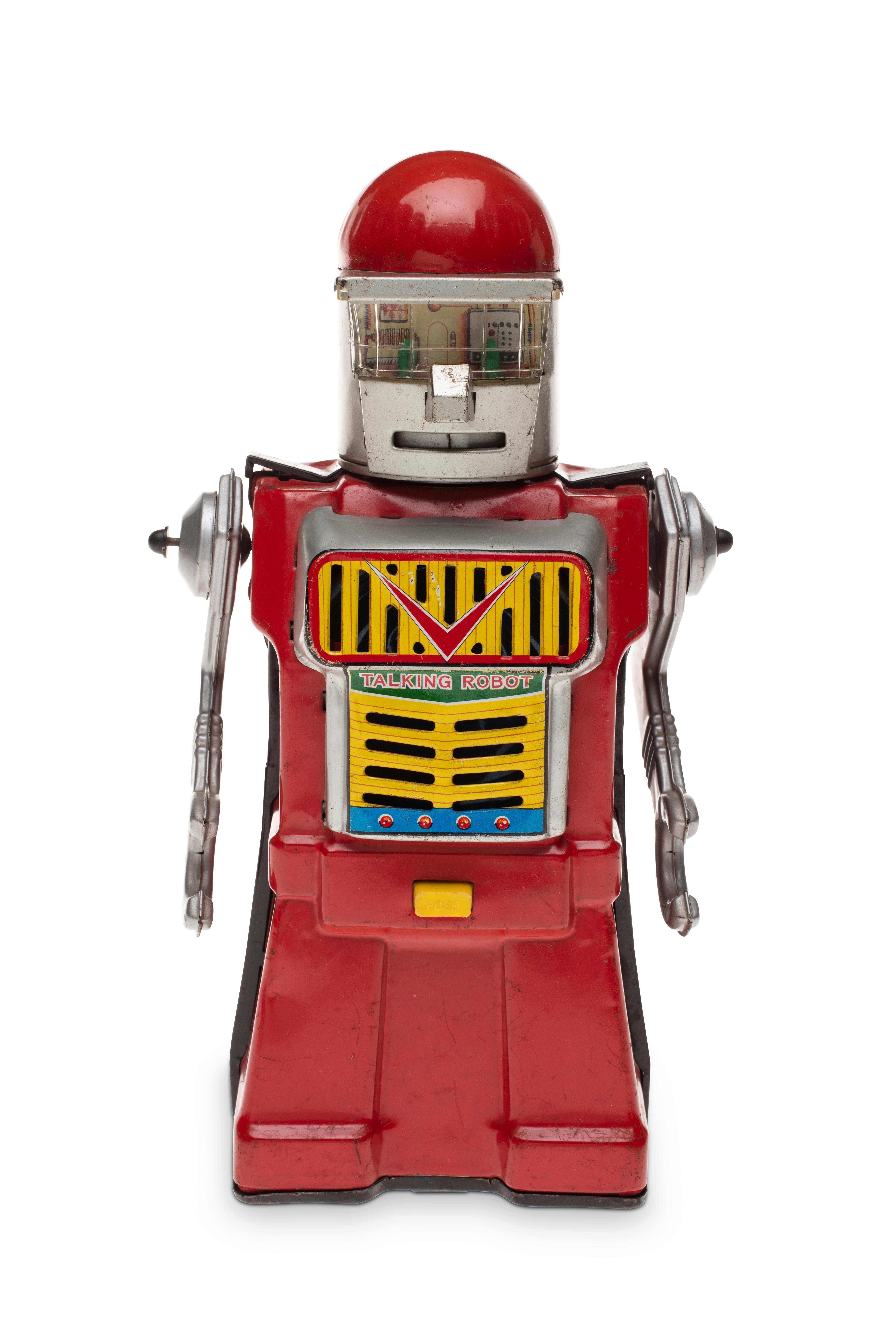 A toy robot made of tin and painted in red, silver and yellow. On the chest are speaker holes with ‘TALKING ROBOT’ printed in the middle.