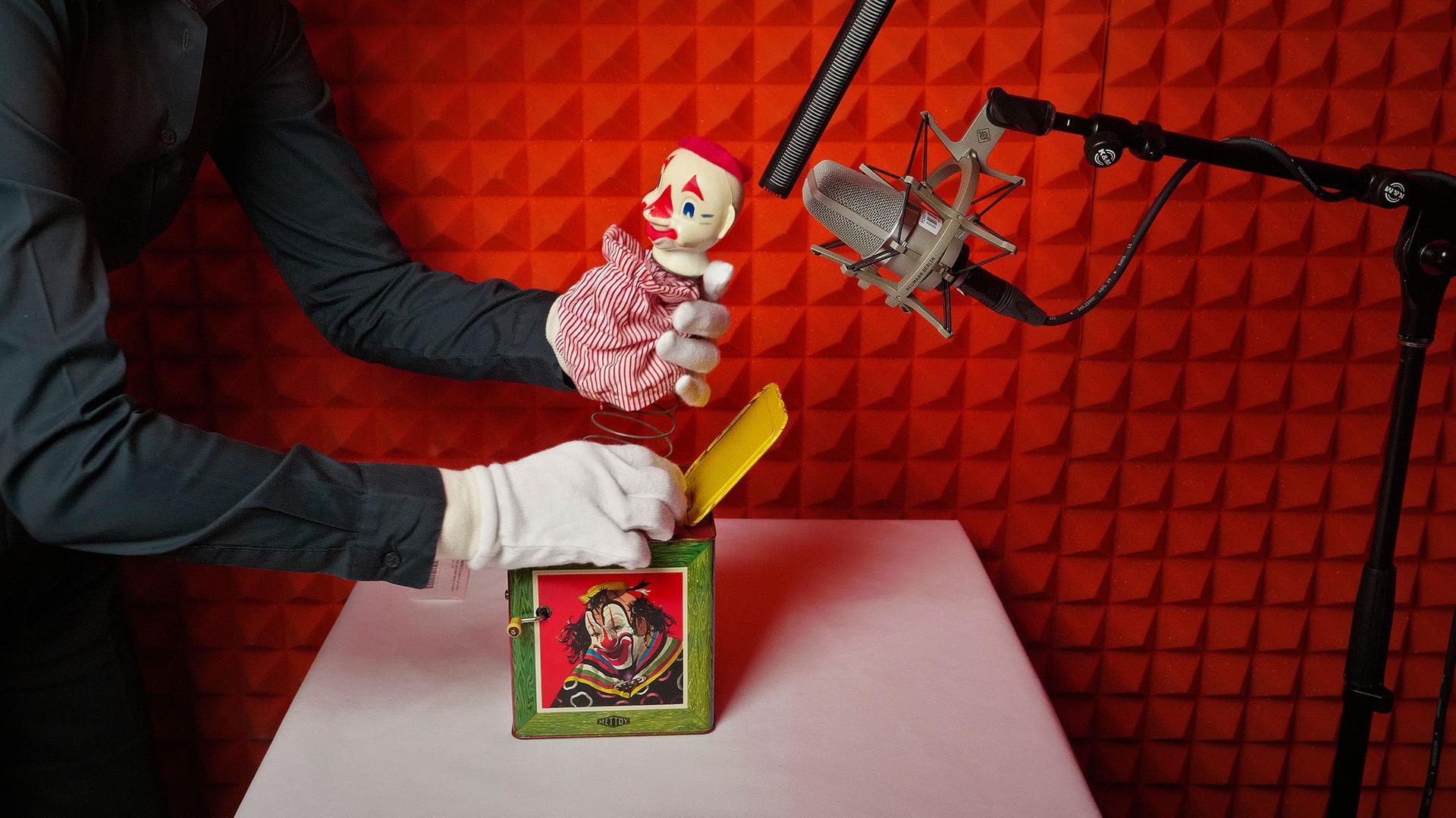 A gloved hand holding a opened jack in a box positioned under two microphones.