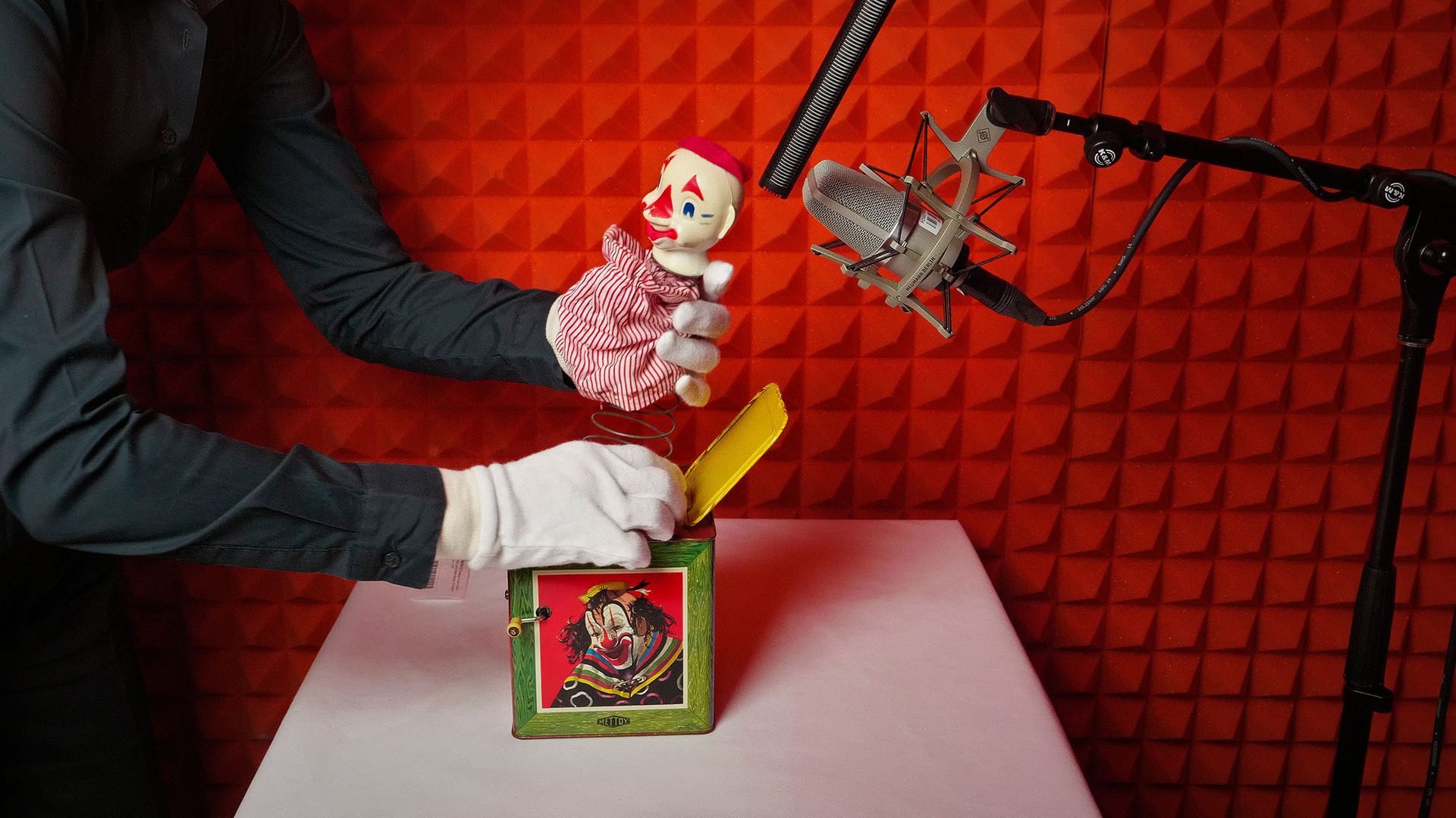 A gloved hand holding a opened jack in a box positioned under two microphones.