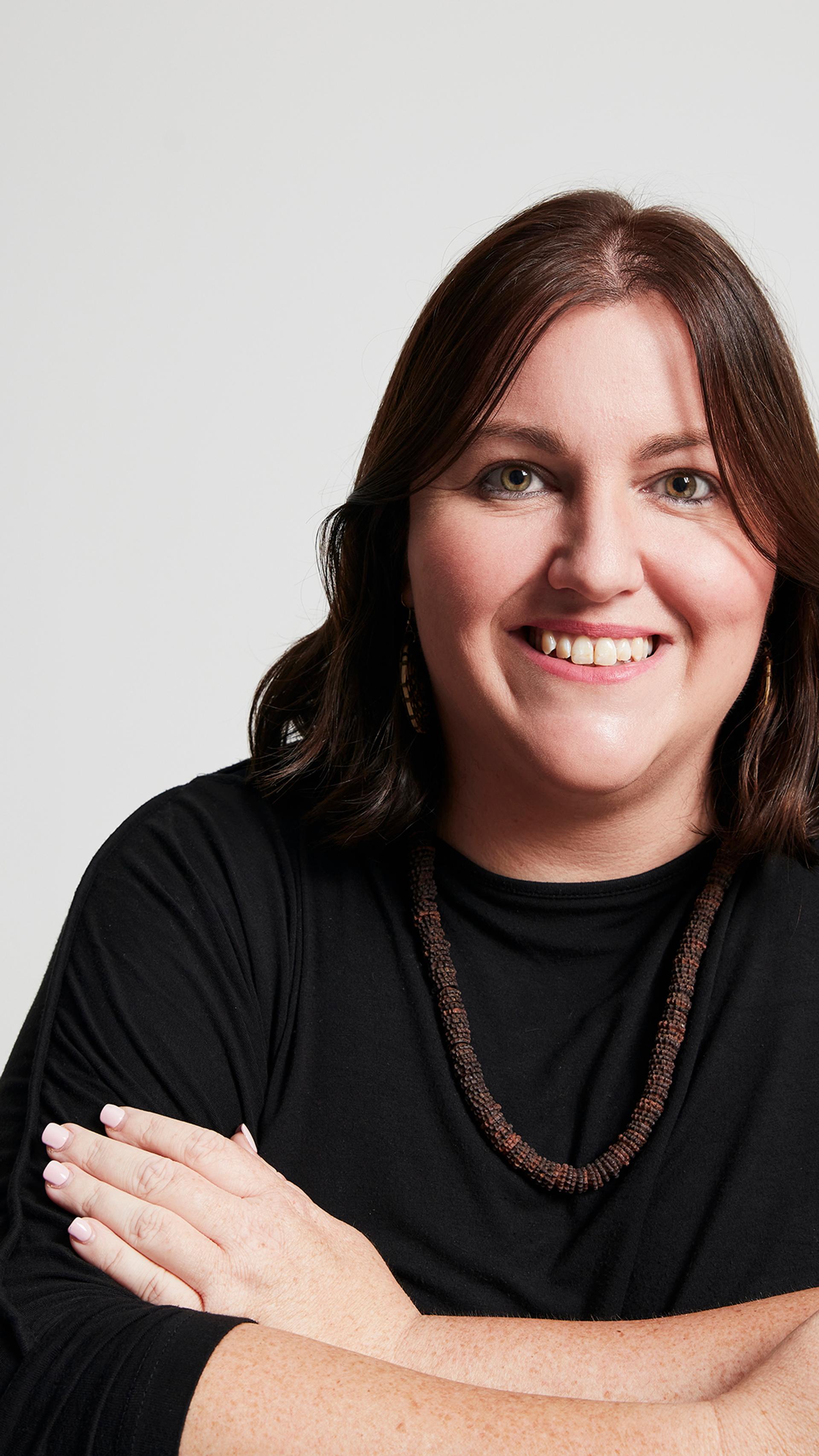 A headshot of a figure wearing a black shirt and necklace