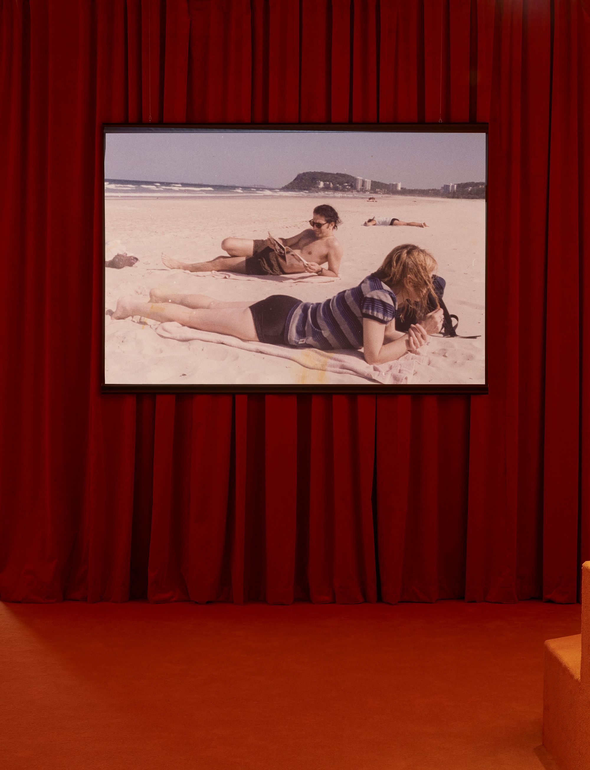 A room with red carpet and a red curtain wall with a screen hanging on it.