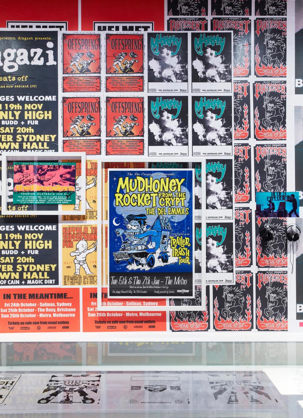 A wall of brightly coloured band posters. The poster in the middle is blue and has the band name ‘Mudhoney’ on it.