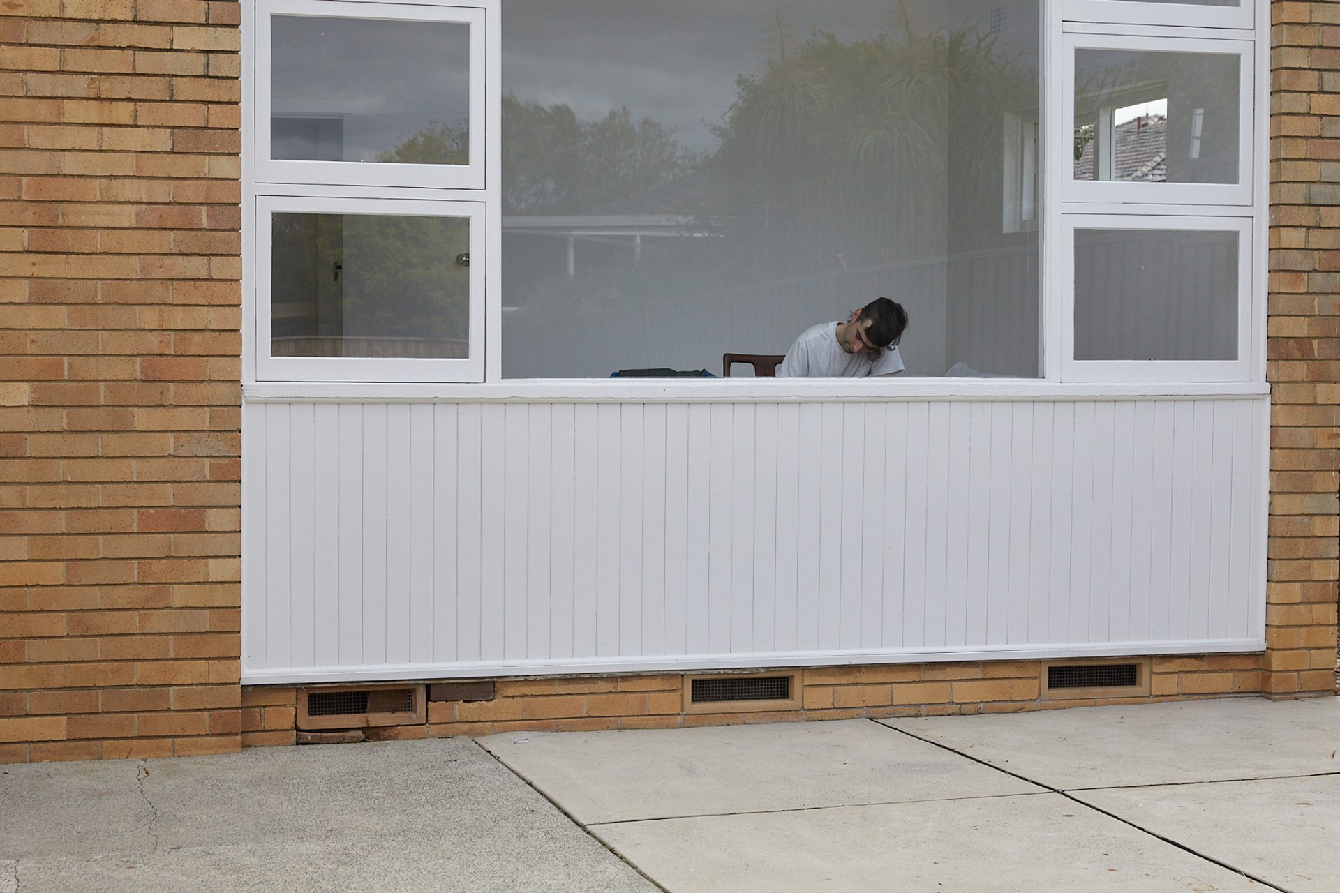 Figure hunched over through the window of a house