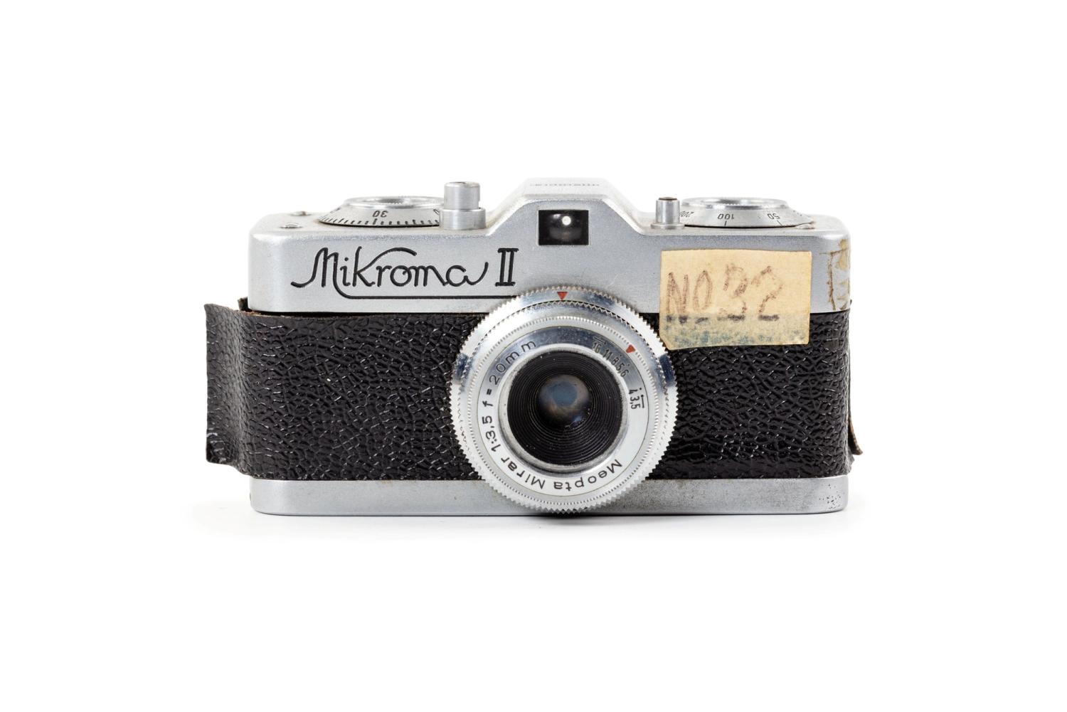 A silver and black film camera on a white background