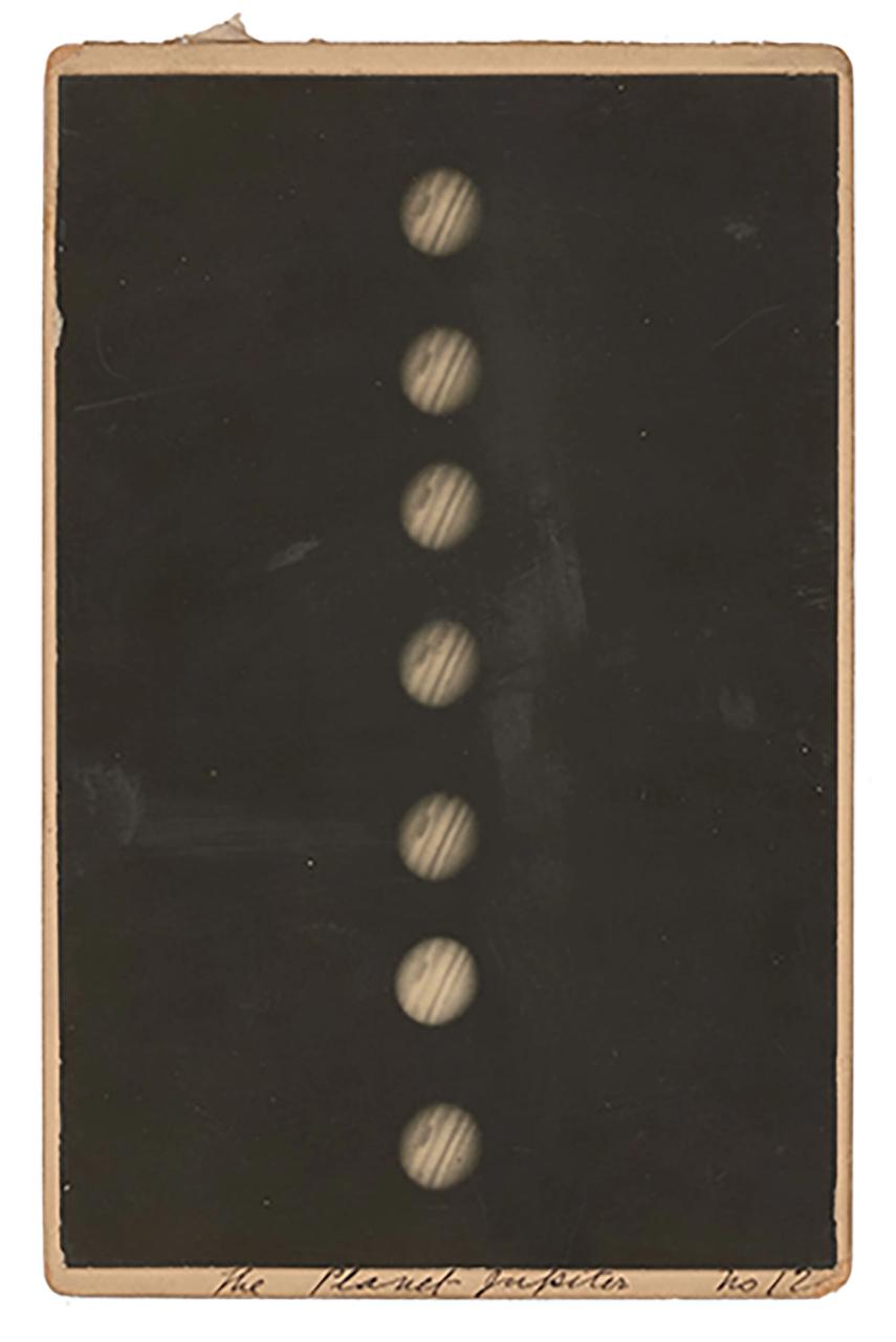 A black and white photograph of Jupiter mounted on a piece of cardboard. The photograph shows several images of Jupiter in a line. The red spot and bands of Jupiter are visible. Handwritten annotations thought to have been made by H C Russell on the mount.