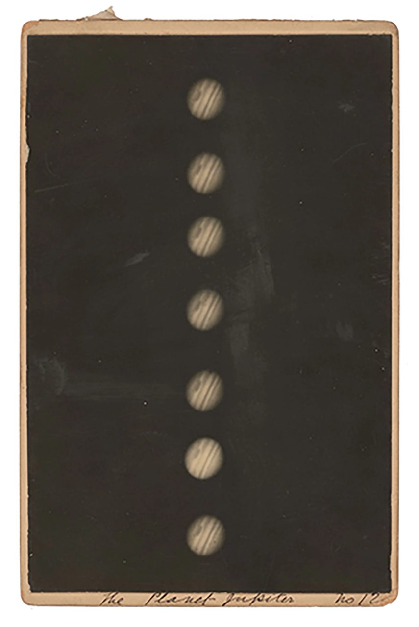 A black and white photograph of Jupiter mounted on a piece of cardboard. The photograph shows several images of Jupiter in a line. The red spot and bands of Jupiter are visible. Handwritten annotations thought to have been made by H C Russell on the mount.